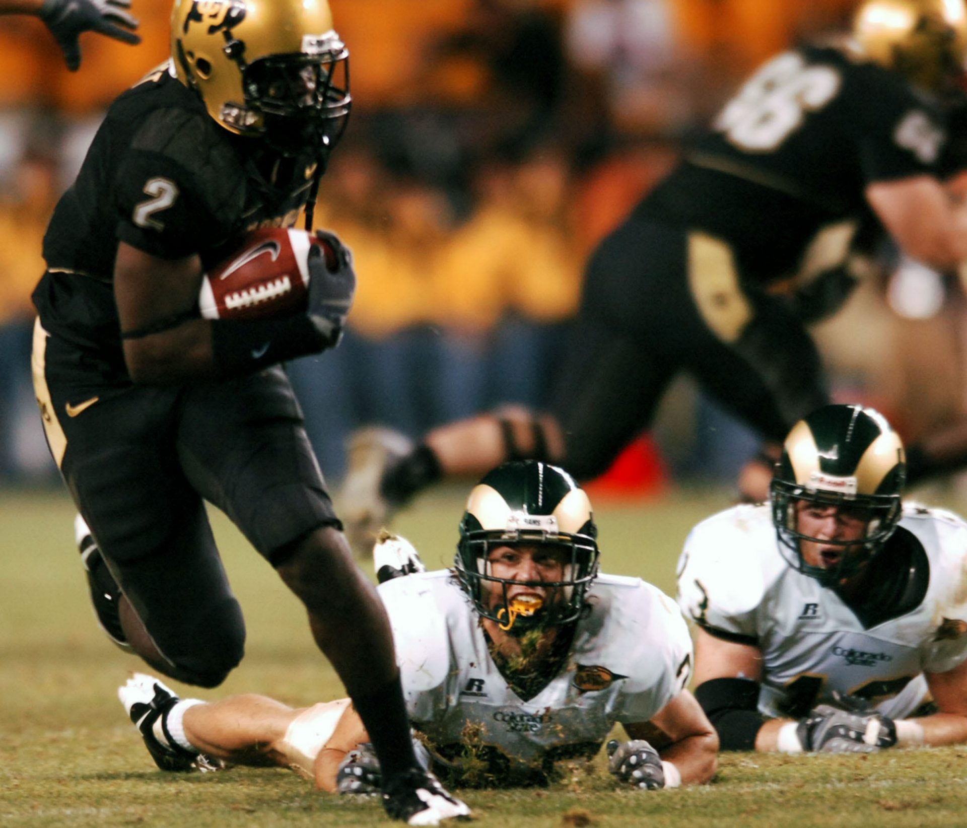 University of Colorado tailback Darrell Scott (2), left, breaks free of Colorado State University defenders Klint Kubiak (20), center, and Mike Pagnotta (13) in the second quarter of action at Invesco Field in Denver on Aug. 31, 2008.