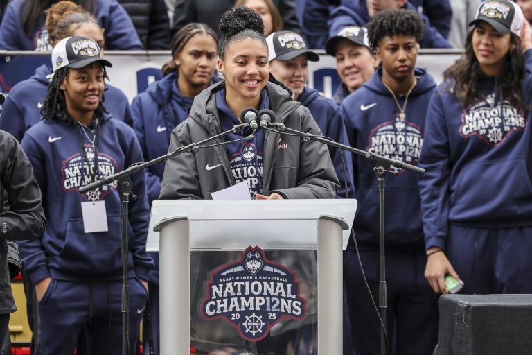 UConn student-athlete Azzi Fudd addresses the crowd while her teammates UConn student-athletes Paige Bueckers, KK Arnold, Sarah Strong and Ayanna Patterson look on during the Final Four champions victory parade and rally outside of the XL Center in Hartford, CT.