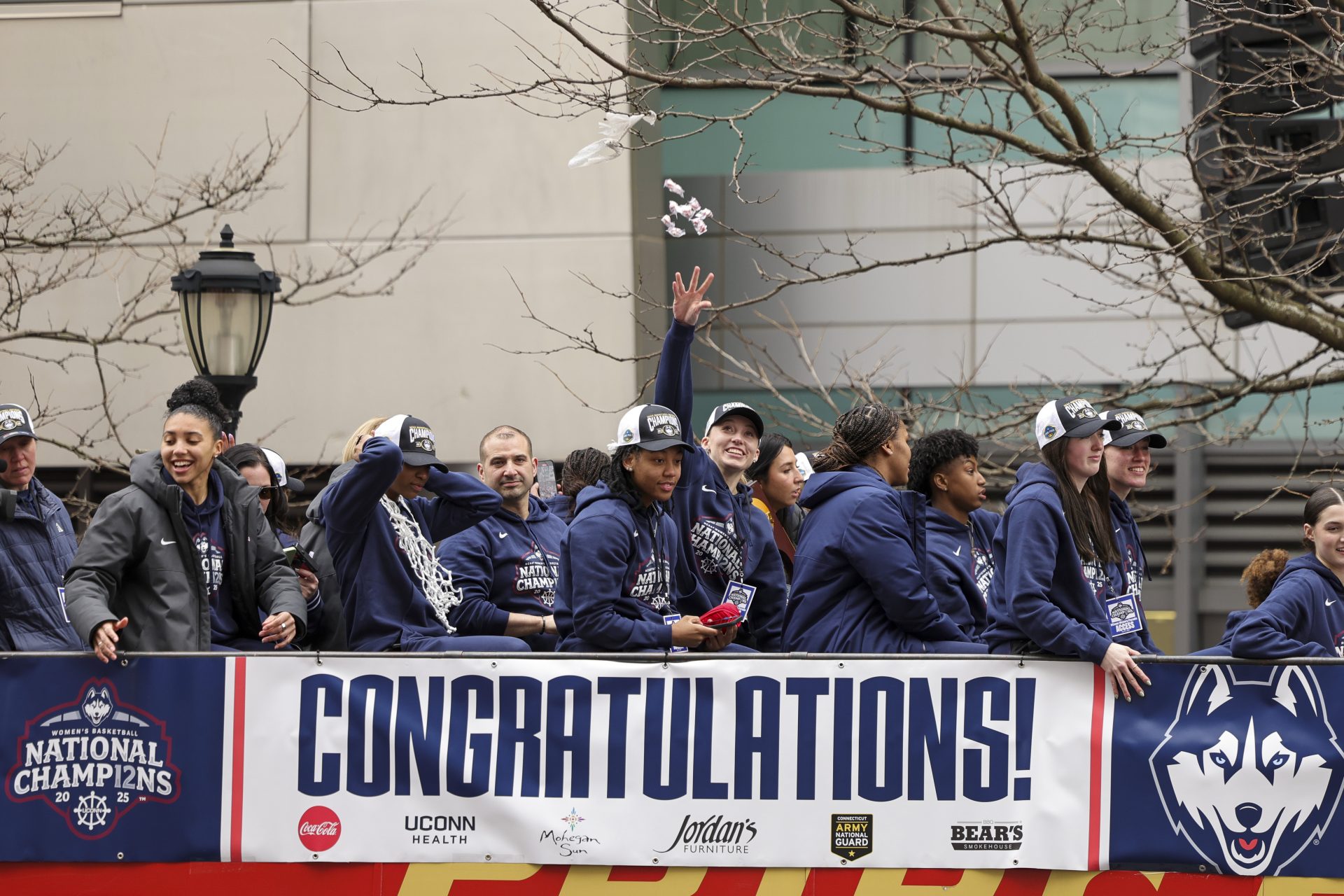 UConn student-athlete Paige Bueckers throws candy to the crowd from the bus over teammate KK Arnold during the Final Four Champions victory parade and rally outside of the XL Center in Hartford, CT.