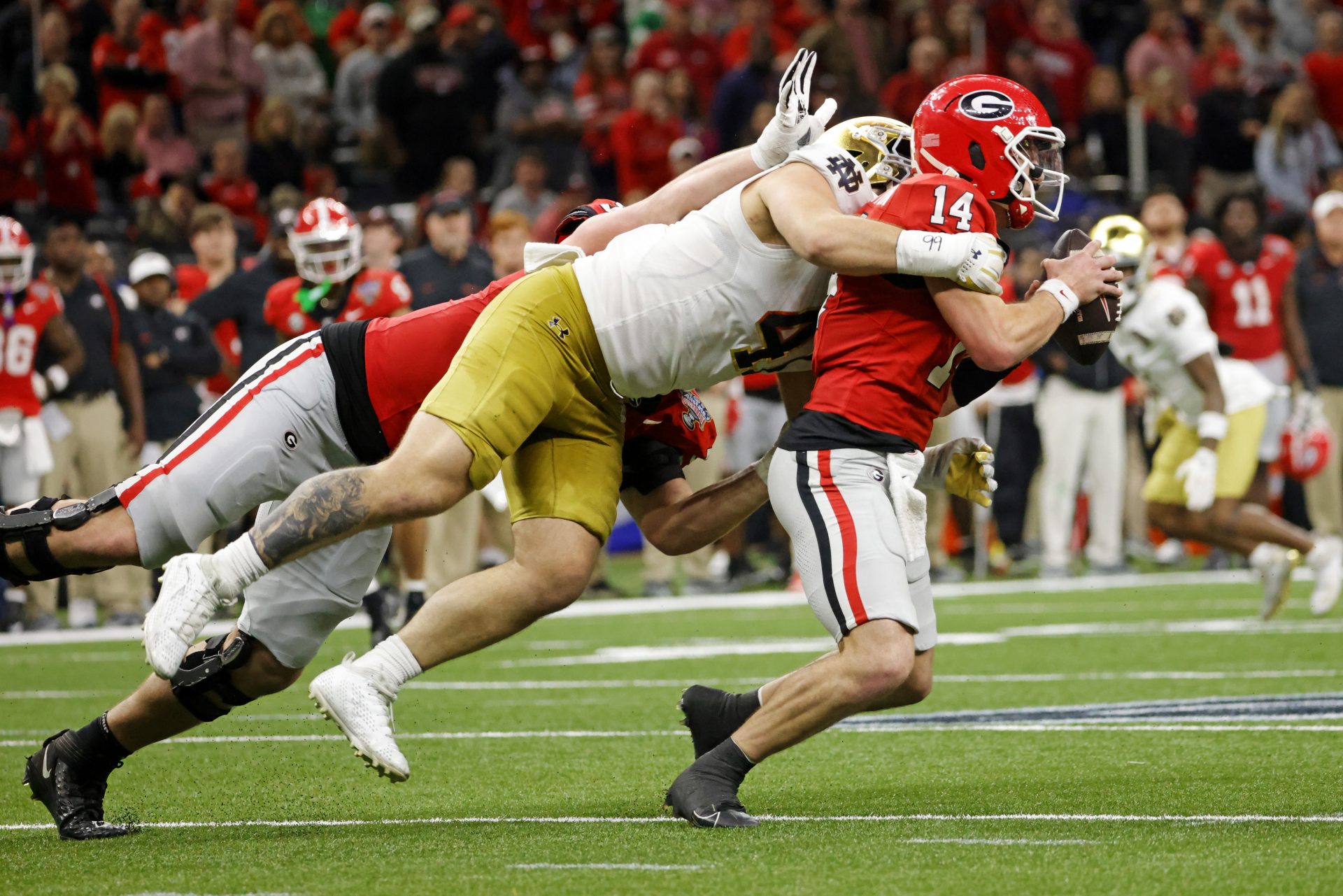 Georgia Bulldogs quarterback Gunner Stockton (14) runs with the ball during the second half as Notre Dame Fighting Irish defensive lineman Donovan Hinish (41) goes for a tackle at Caesars Superdome.
