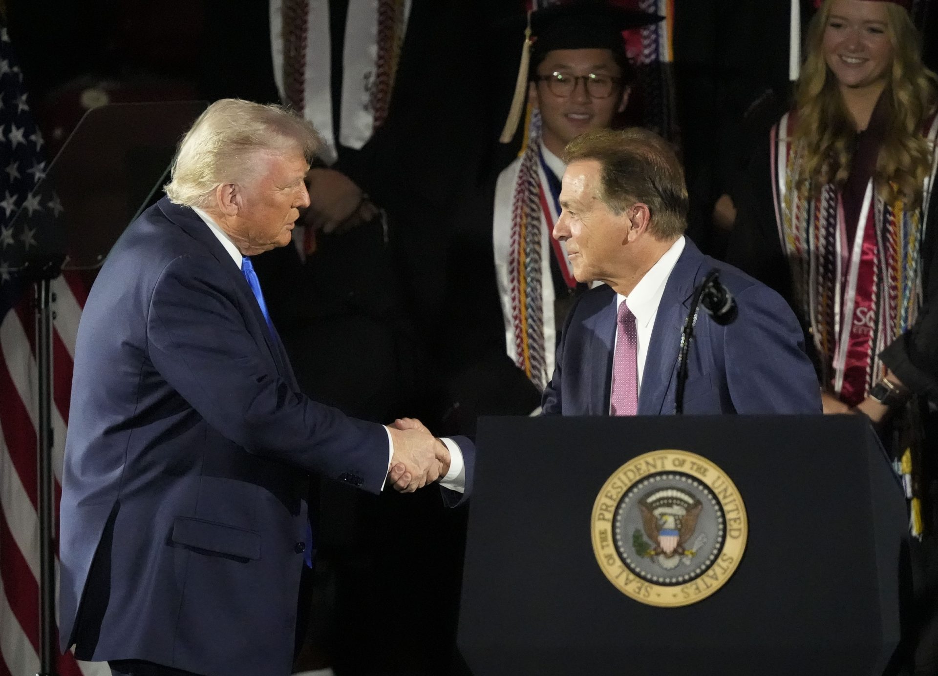 President Donald Trump shakes hands with former Alabama football coach Nick Saban before delivering a special commencement address to University of Alabama graduates at Coleman Coliseum. Graduation occurs over the weekend.