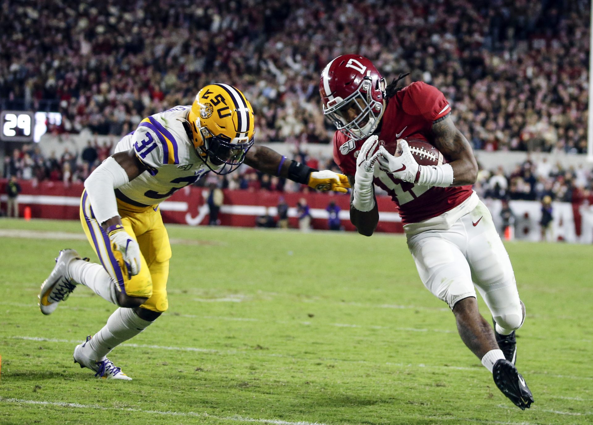 Alabama Crimson Tide wide receiver Jaylen Waddle (17) carries the ball as LSU Tigers safety Cameron Lewis (31) closes in for the tackle during the second half of an NCAA college football game at Bryant-Denny Stadium. LSU won 46-41.