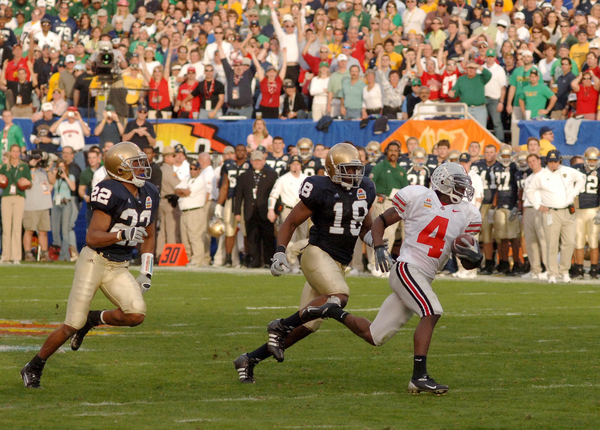 Ohio State Buckeyes split end (4) Santonio Holmes runs away from Notre Dame Fighting Irish defenders (18) Chinedum Ndukwe and (22) Ambrose Wooden for a touchdown during the 2nd quarter of the Tostitos Fiesta Bowl at Sun Devil Stadium in Tempe, Arizona.