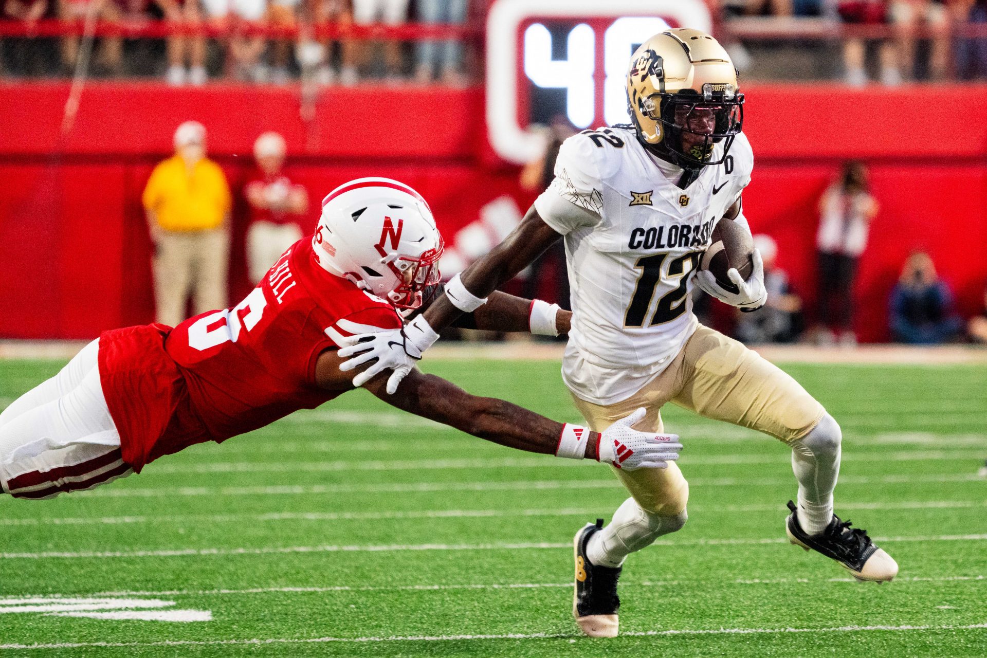 Colorado Buffaloes wide receiver Travis Hunter (12) stiff arms Nebraska Cornhuskers defensive back Tommi Hill (6) during the second quarter at Memorial Stadium.