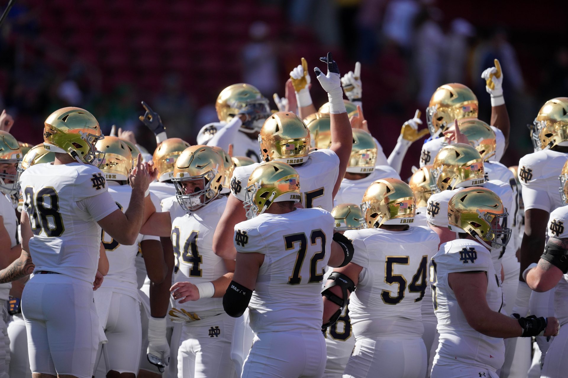 Notre Dame Fighting Irish players huddle in gold helmets against the Southern California Trojans at United Airlines Field at Los Angeles Memorial Coliseum.