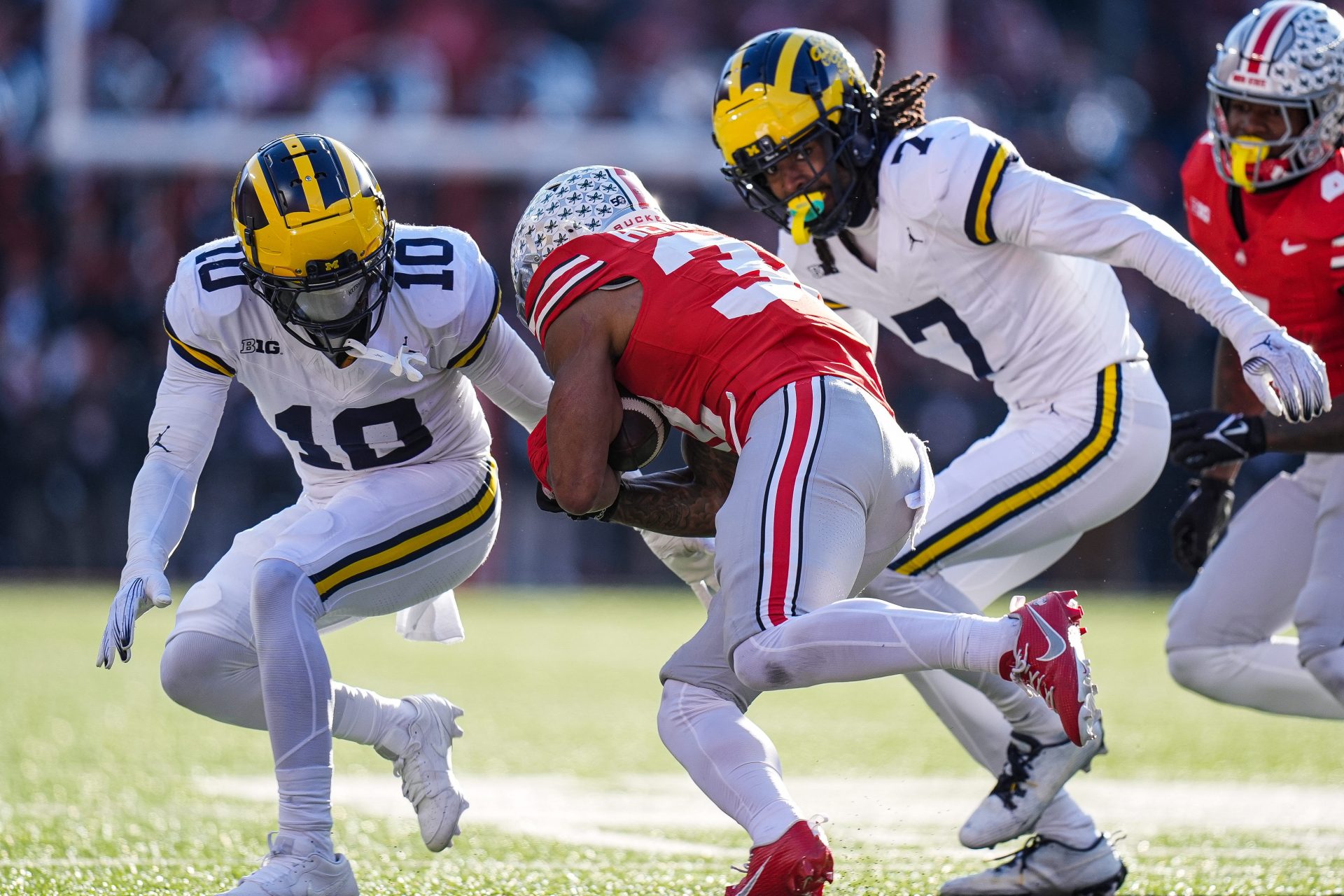 Michigan defensive back Zeke Berry (10), left, and defensive back Makari Paige (7) tackle Ohio State safety Brenten Jones (32) during the second half at Ohio Stadium in Columbus, Ohio on Saturday, Nov. 30, 2024.