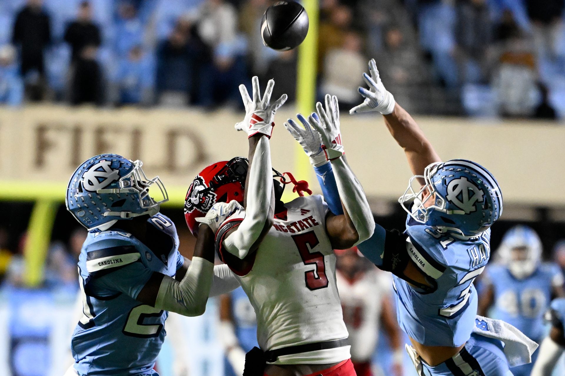 North Carolina State Wolfpack wide receiver Noah Rogers (5) catches a 44 yard pass as North Carolina Tar Heels defensive backs Marcus Allen (29) and Will Hardy (31) defend in the fourth quarter at Kenan Memorial Stadium.
