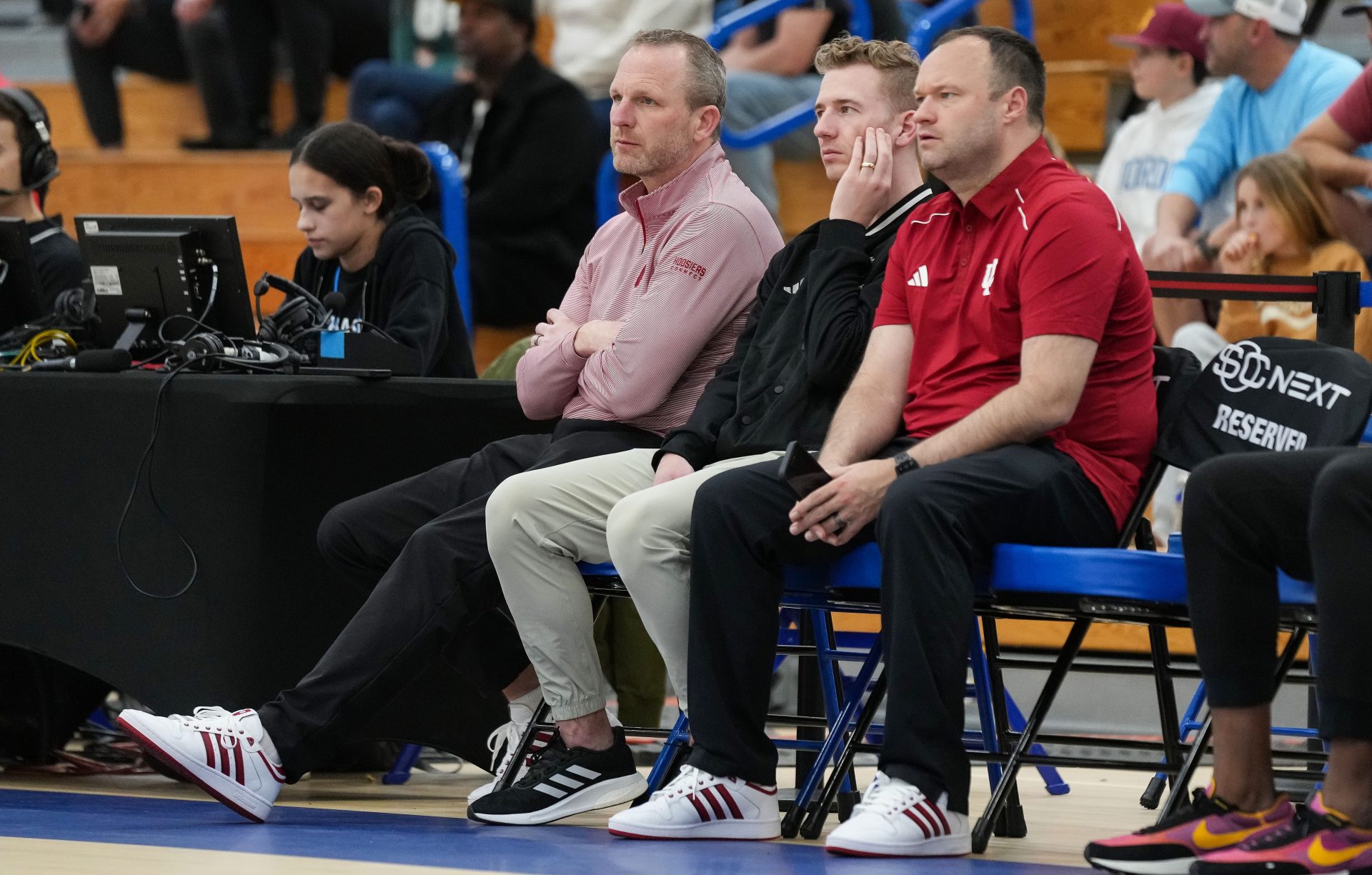 Indiana University men's head basketball coach Darian DeVries (left), Nick Norton and Drew Adams watch the game Wednesday, April 2, 2025, during the first game of the Chipotle Nationals at Hamilton Southeastern High School in Fishers.