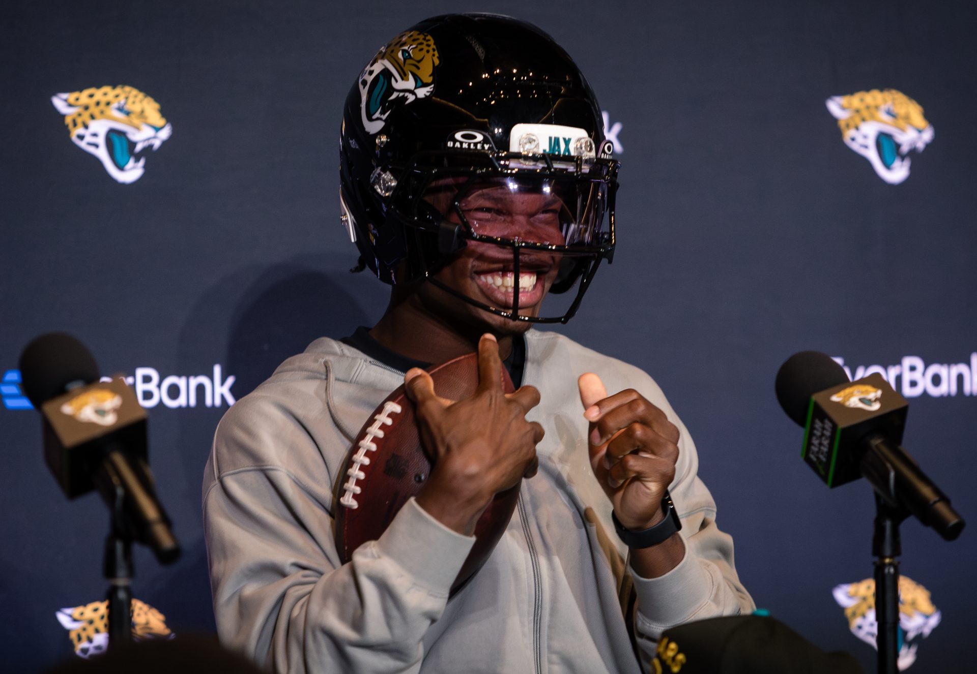 Jacksonville Jaguars first round draft pick Travis Hunter puts on a helmet during a press conference at Miller Electric Center.
