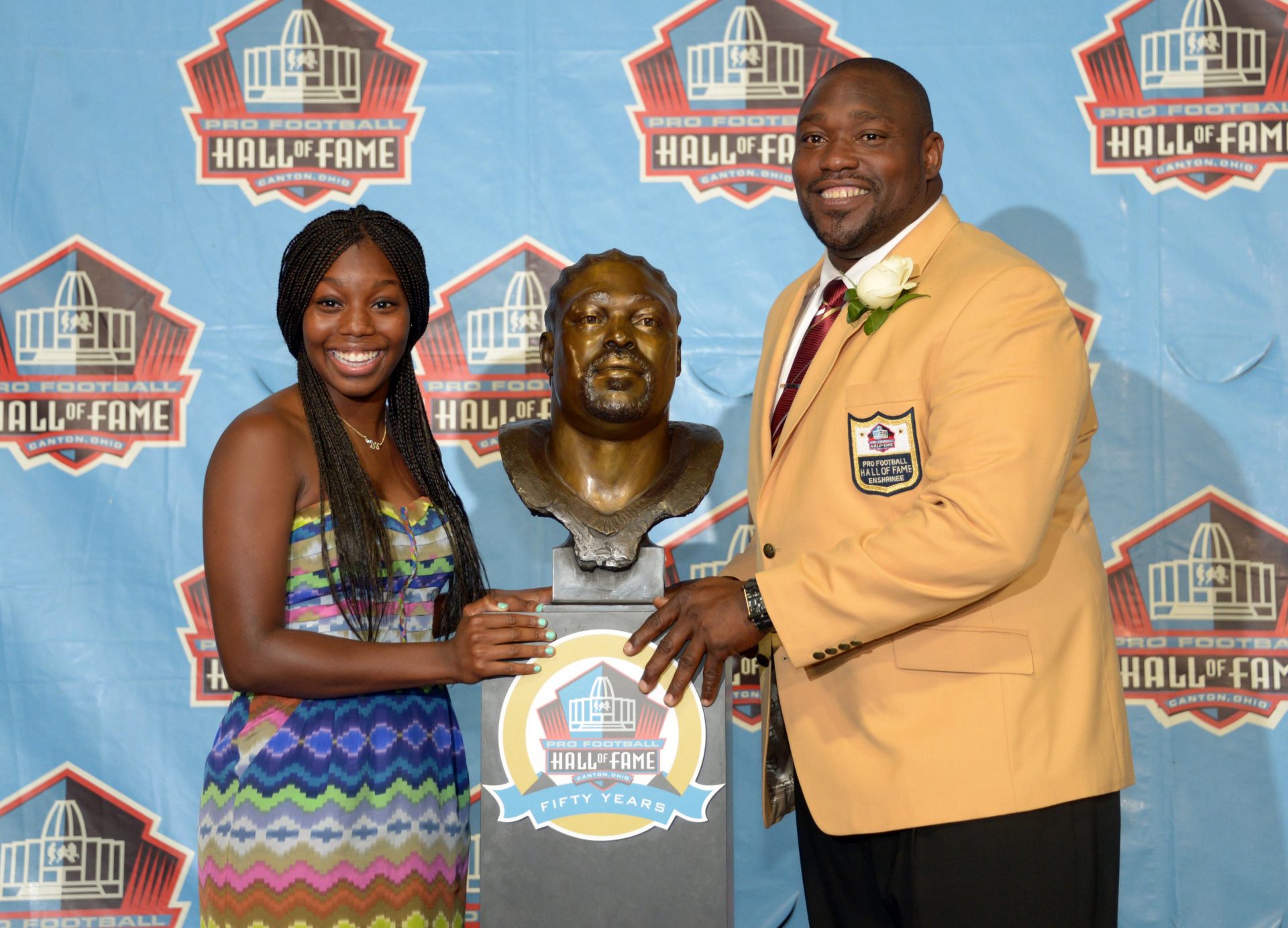 Warren Sapp (left) and daughter Mercedes Sapp pose with his bust of the elder Sapp at the 2013 Pro Football Hall of Fame Enshrinement at Fawcett Stadium.