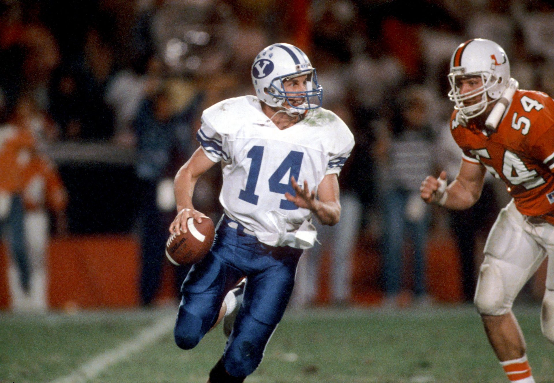 FILE PHOTO; Brigham Young quarterback #14 TY DETMER  is chased by Miami Hurricanes defensive end #54 BILL HAWKINS during the 1988 season at the Orange Bowl.  Miami defeated BYU 41-17.