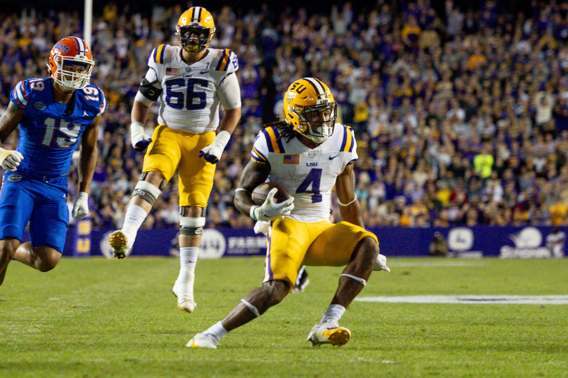 LSU Tigers running back John Emery Jr. (4) rushes against Florida Gators defensive end T.J. Searcy (19) during the first half at Tiger Stadium.
