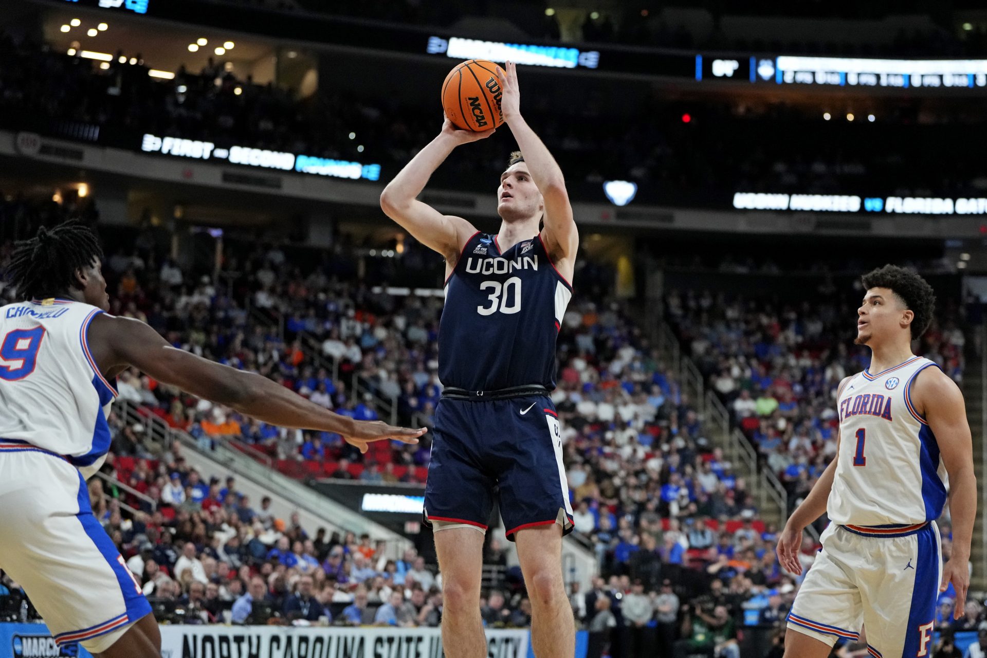 Connecticut Huskies forward Liam McNeeley (30) drives to the basket during the first half against Florida Gators center Rueben Chinyelu (9) in the second round of the NCAA Tournament at Lenovo Center.