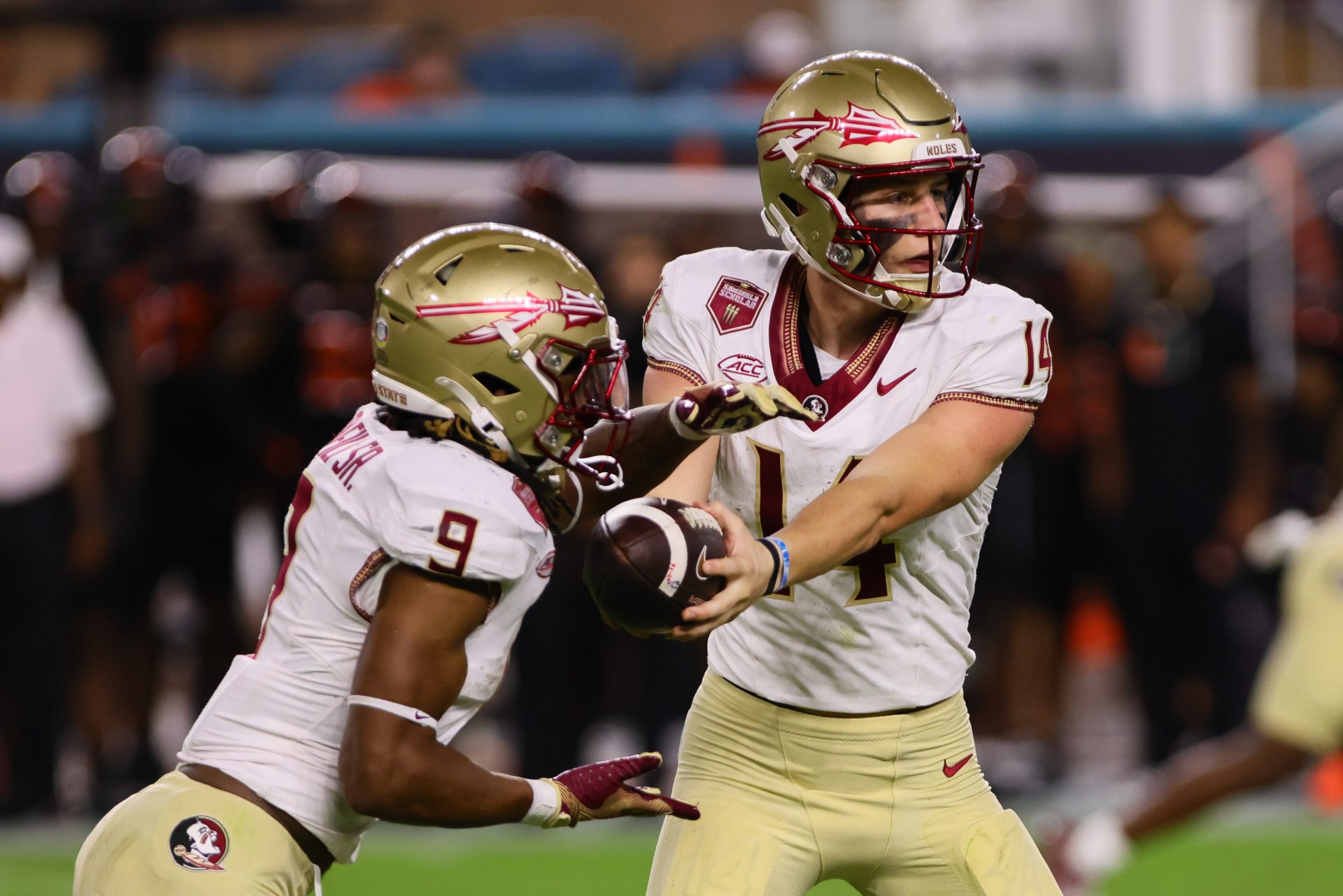 Florida State Seminoles running back Lawrance Toafili (9) takes a handoff from quarterback Luke Kromenhoek (14) against the Miami Hurricanes during the third quarter at Hard Rock Stadium.