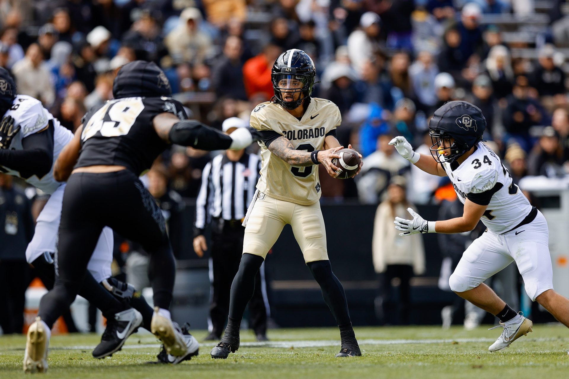 Colorado Buffaloes quarterback Kaidon Salter (3) hands the ball off to running back Titus Bautista (34) as defensive end Quency Wiggins (49) defends during the spring game at Folsom Field.
