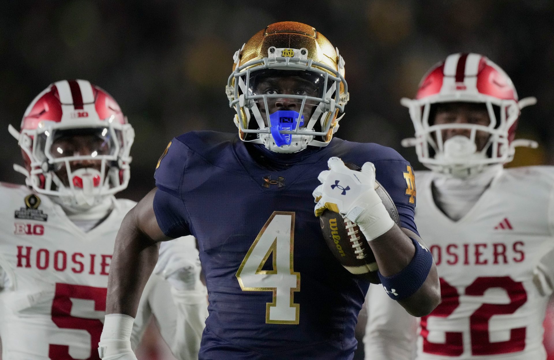 Notre Dame Fighting Irish running back Jeremiyah Love (4) scores a touchdown while being chased by Indiana Hoosiers defensive back D'Angelo Ponds (5) and Indiana Hoosiers defensive back Jamari Sharpe (22) during the first half of a game between the Indiana Hoosiers and the Notre Dame Fighting Irish in first round of the College Football Playoff on Friday, Dec. 20, 2024, in South Bend.