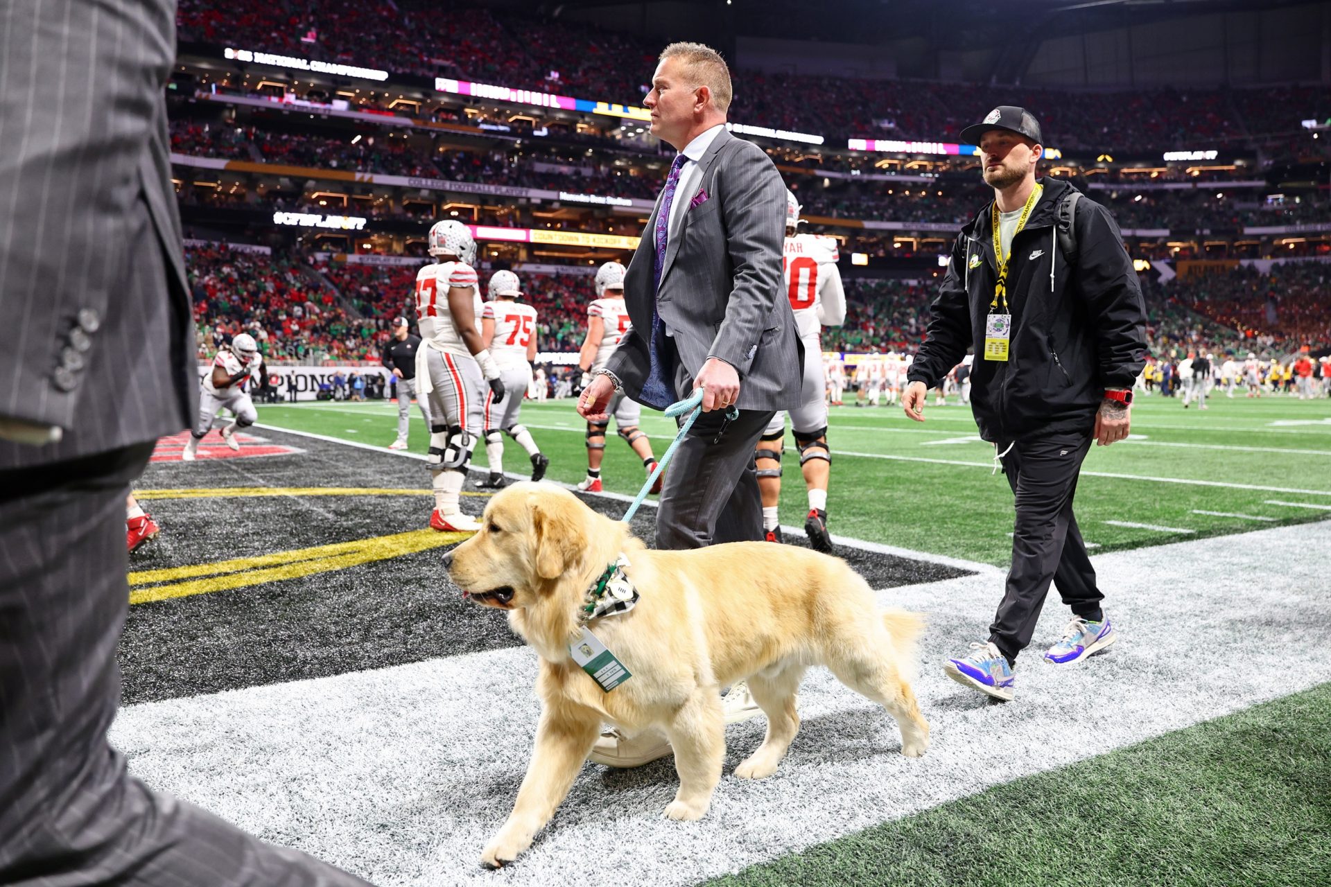 Kirk Herbstreit walks on the field wit his dog before the CFP National Championship college football game at Mercedes-Benz Stadium.