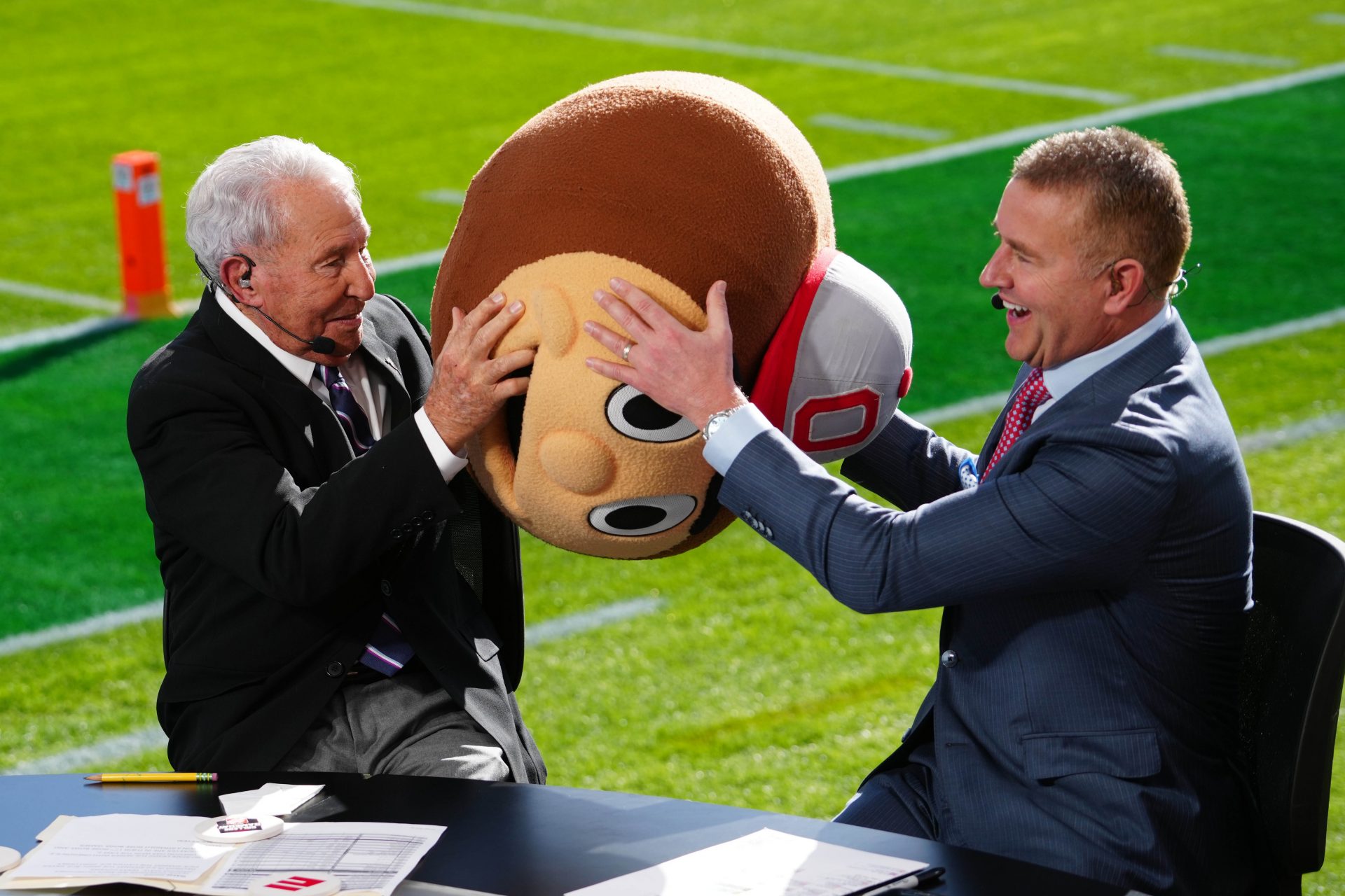 Lee Corso (left) wears a Buckeyes mascot head as Kirk Herbstreit watches at Rose Bowl Stadium.