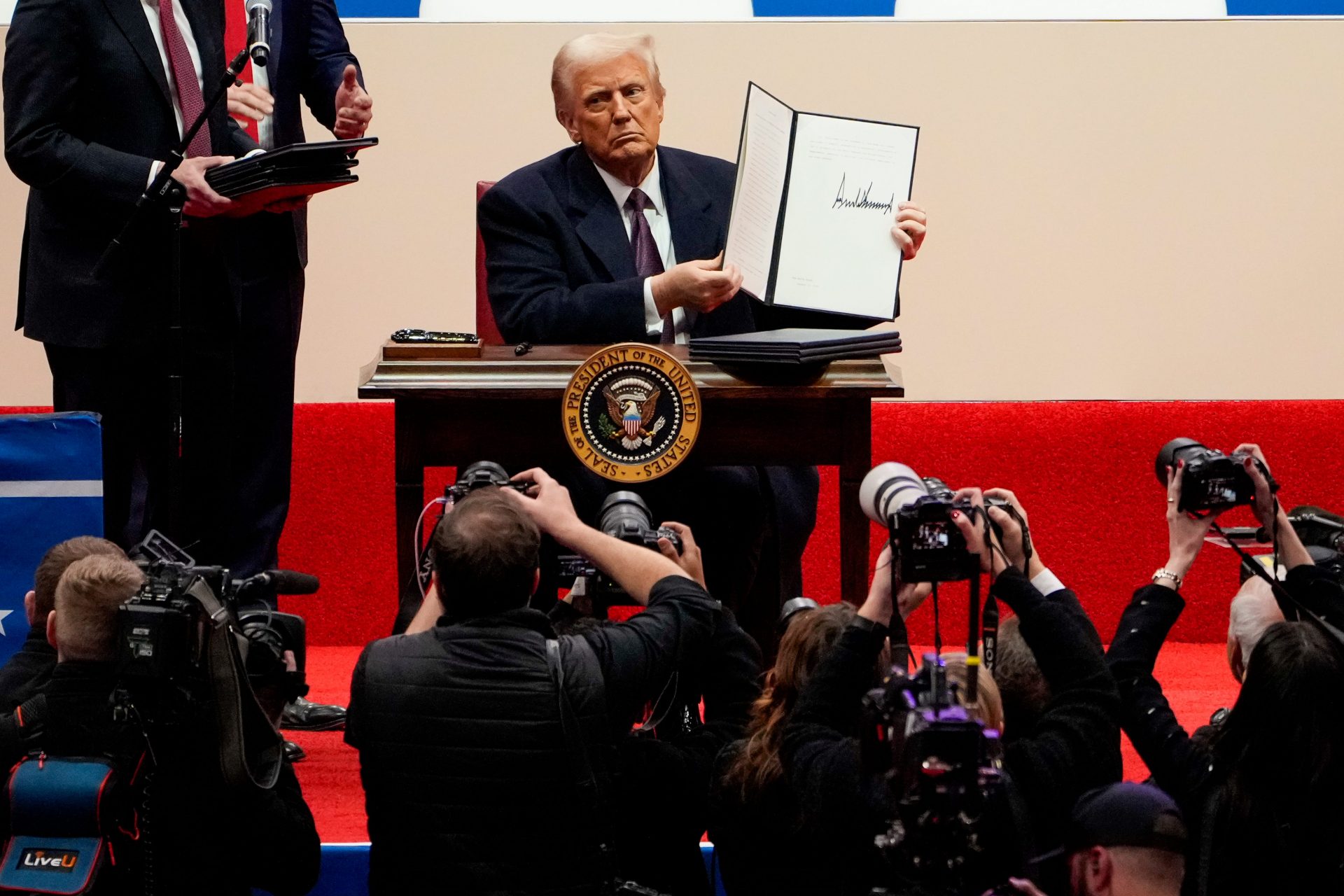 President Donald Trump signs a stack of executive orders on stage during his inauguration parade at Capital One Arena in Washington on Monday, Jan. 20, 2025.