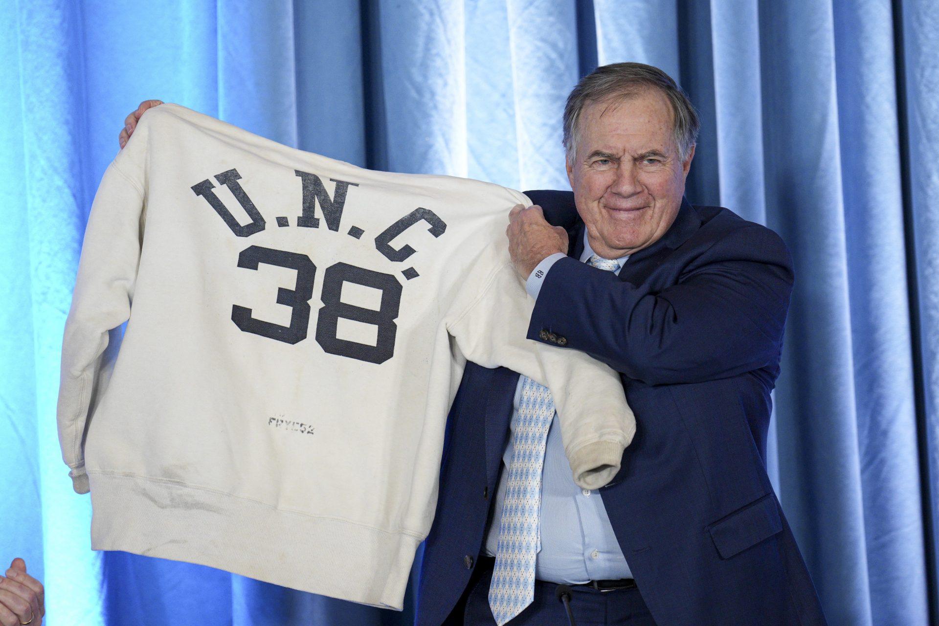 North Carolina Tar Heels new head coach Bill Belichick holds up the sweatshirt worn by his father when he was an assistant coach at New North Carolina Tar Heels new at Loudermilk Center for Excellence.