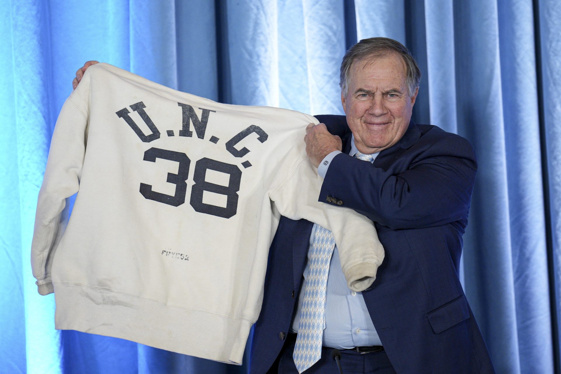 North Carolina Tar Heels new head coach Bill Belichick holds up the sweatshirt worn by his father when he was an assistant coach at New North Carolina Tar Heels new at Loudermilk Center for Excellence.