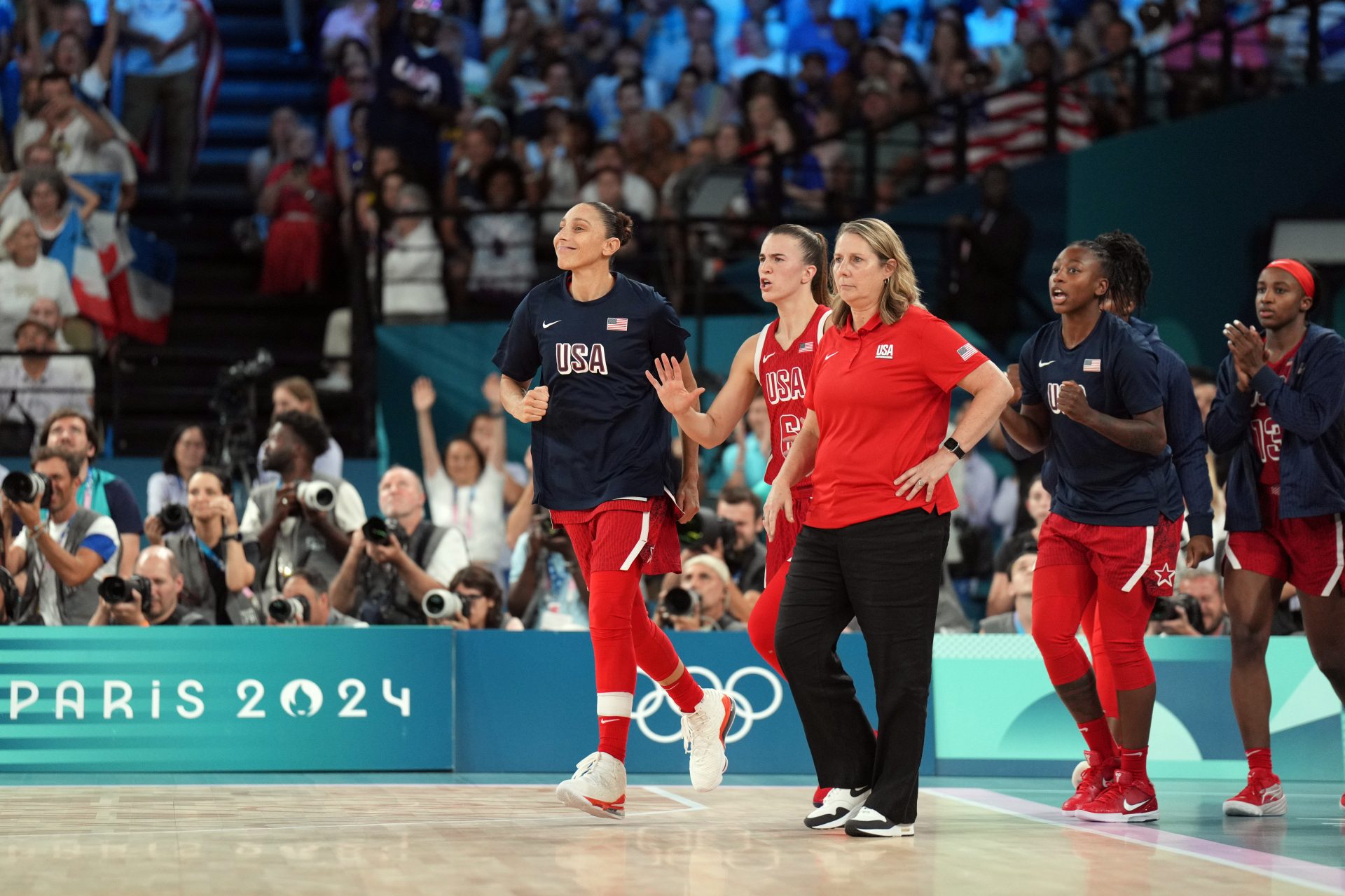 United States shooting guard Diana Taurasi (12) and guard Sabrina Ionescu (6) and head coach Cheryl Reeve react after defeating France in the women's gold medal game during the Paris 2024 Olympic Summer Games at Accor Arena.