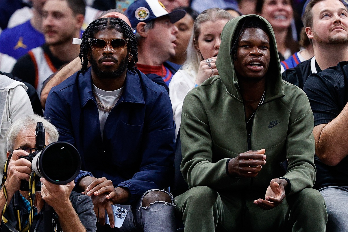 University of Colorado Buffaloes football players Shedeur Sanders (L) and Travis Hunter (R) watch during the third period between the Denver Nuggets and the Los Angeles Lakers at Ball Arena.