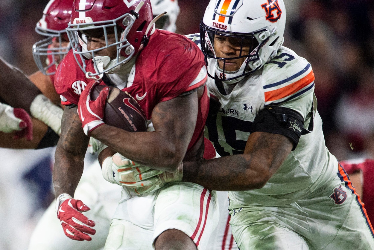 Auburn Tigers defensive lineman Keldric Faulk (15) takes down Alabama Crimson Tide running back Jam Miller (26) as Auburn Tigers take on Alabama Crimson Tide at Bryant-Denny Stadium in Tuscaloosa, Ala., on Saturday, Nov. 30, 2024. Alabama Crimson Tide defeated Auburn Tigers 28-14.