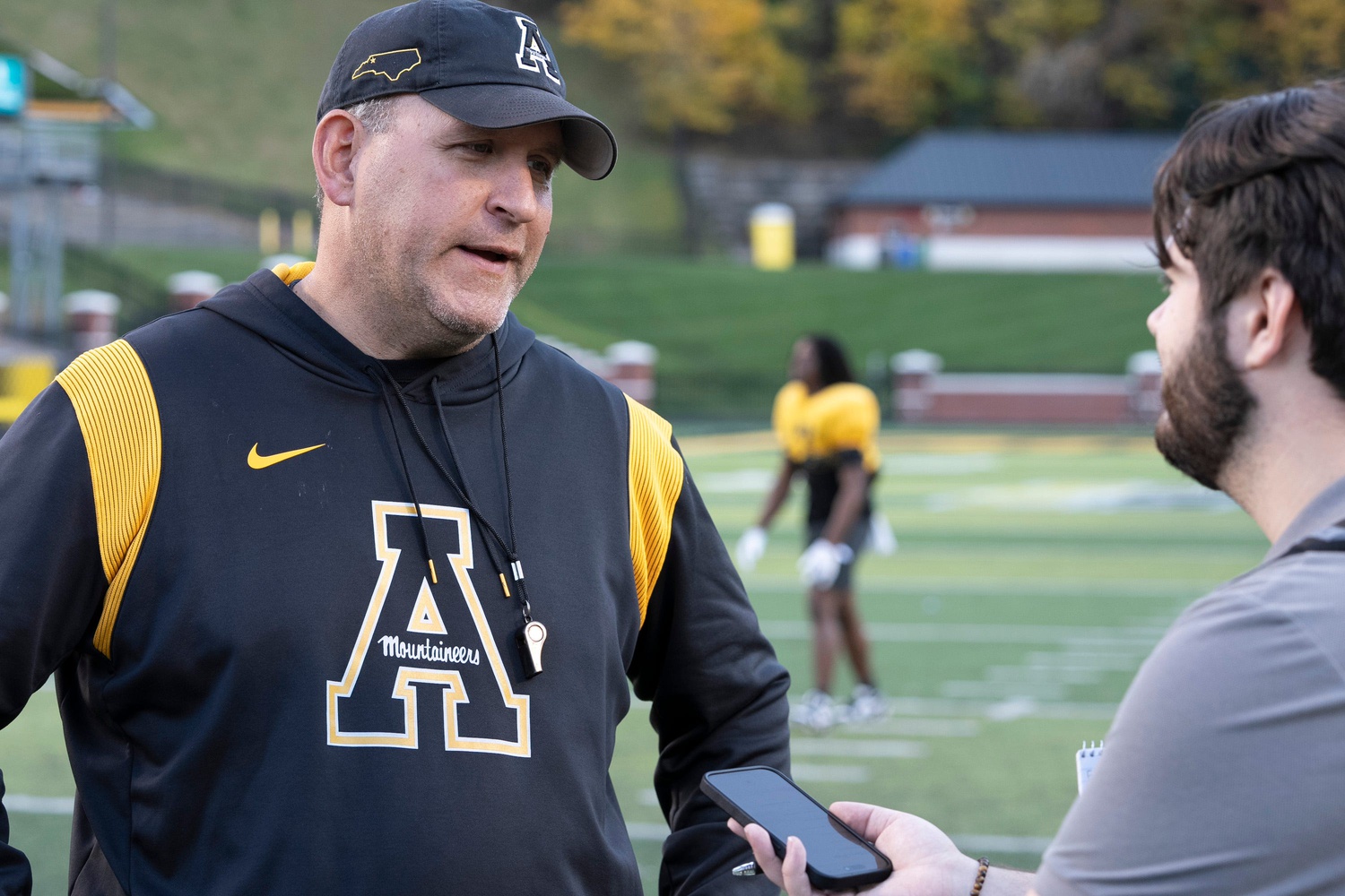 Head Coach Shawn Clark speaks to Asheville Citizen-Times sports reporter Evan Gerike after the AppState Mountaineers' football practice at Appalachian State University in Boone, NC, on Wednesday, Oct. 23, 2024.