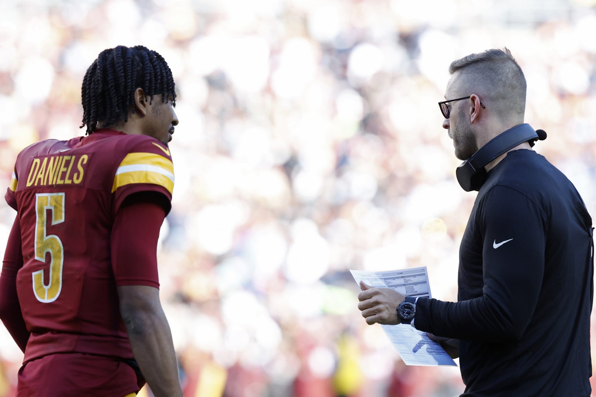 Washington Commanders quarterback Jayden Daniels (5) talks with Commanders offensive coordinator Kliff Kingsbury (R) against the against the Dallas Cowboys at Northwest Stadium.