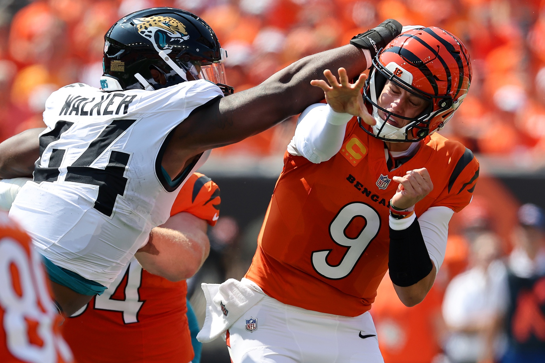 Cincinnati Bengals quarterback Joe Burrow (9) takes a hit to the head from Jacksonville Jaguars defensive end Travon Walker (44) during the first quarter at Paycor Stadium.