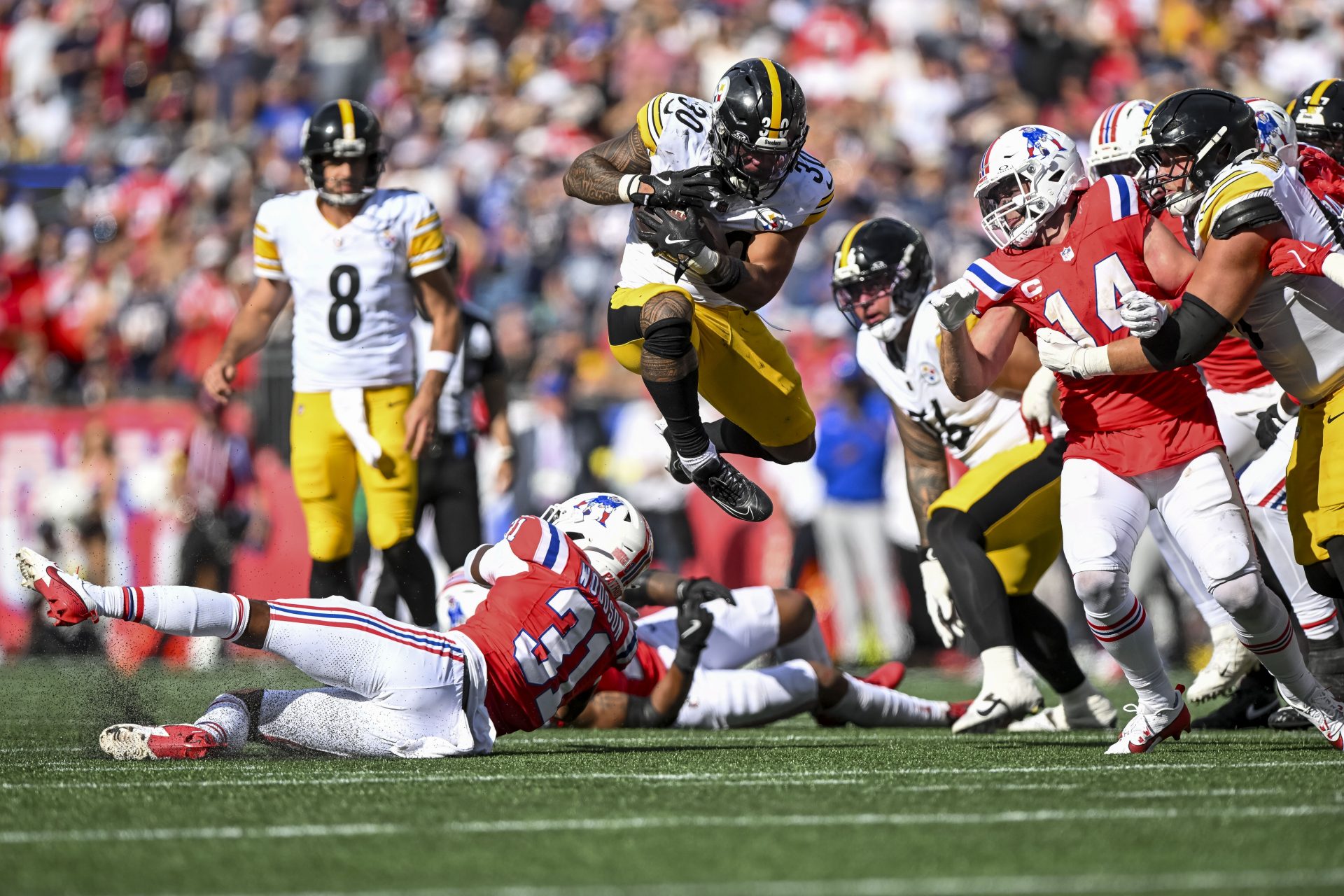 Pittsburgh Steelers running back Jaylen Warren (30) jumps over New England Patriots safety Craig Woodson (31) during the fourth quarter at Gillette Stadium.