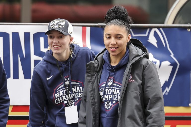 UConn student-athlete Paige Bueckers and UConn student-athlete Azzi Fudd walk onto the stage during the Final Four Champions victory parade and rally outside of the XL Center in Hartford, CT.