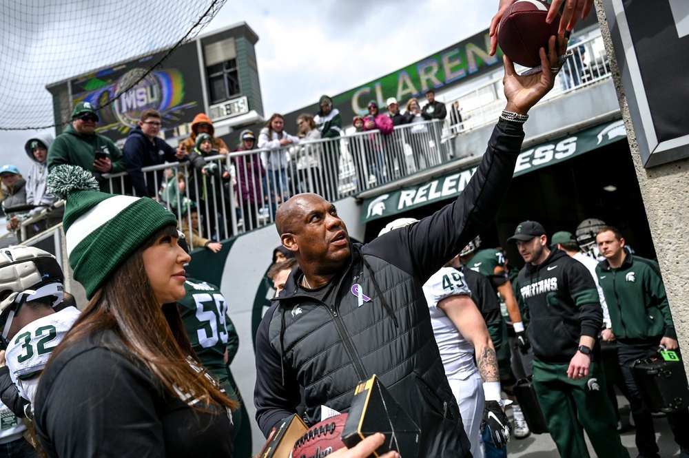 Michigan State's head coach Mel Tucker, right, hands back a signed football for fans on Saturday, April 16, 2022, during the spring game at Spartan Stadium in East Lansing. At left is honorary captain Brenda Tracy, sexual violence prevention educator.