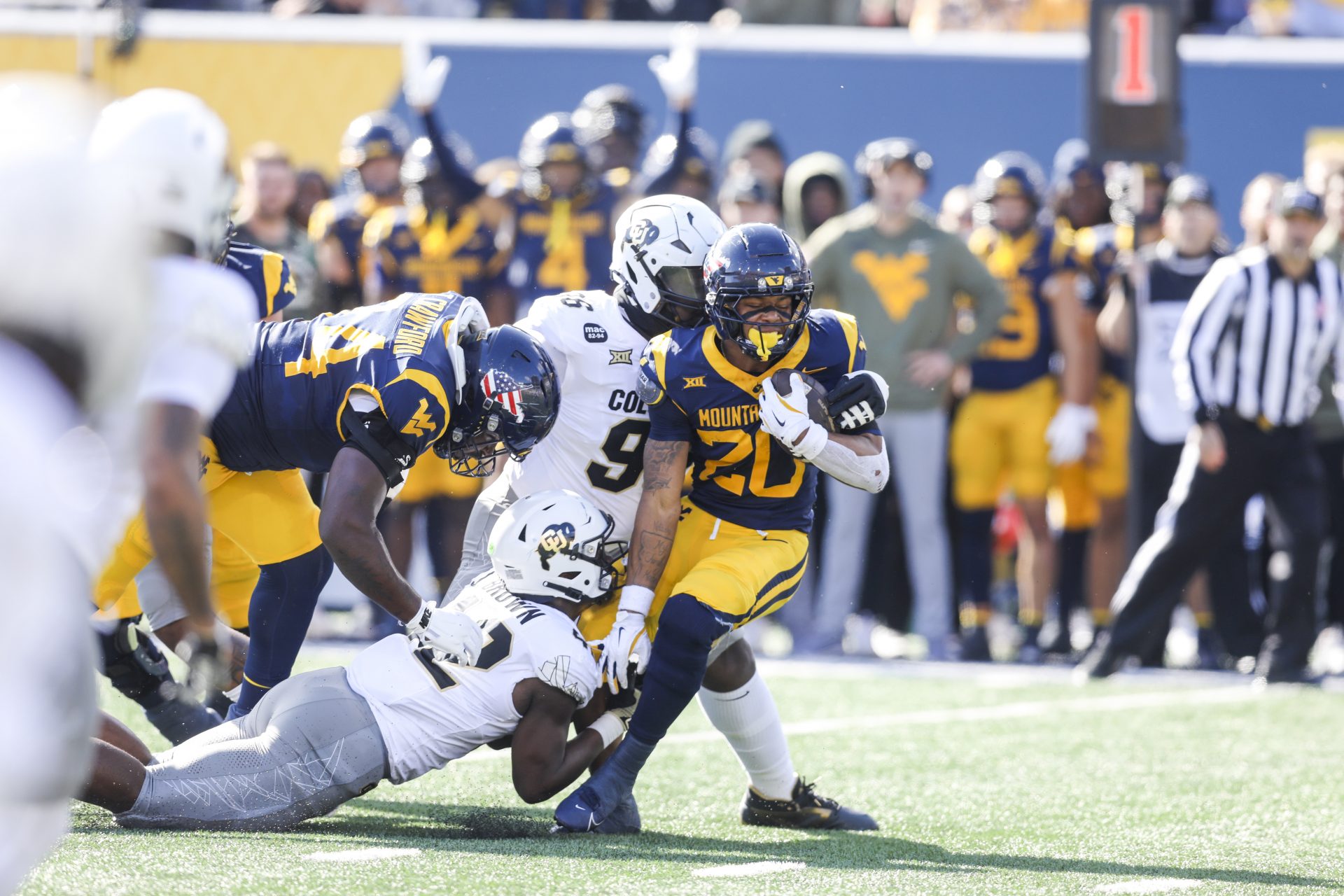 West Virginia Mountaineers running back Diore Hubbard (20) runs the ball as he’s tackled by Colorado Buffaloes linebacker Jeremiah Brown (42) and Colorado Buffaloes defensive lineman Jehiem Oatis (96) during the first quarter at Milan Puskar Stadium.
