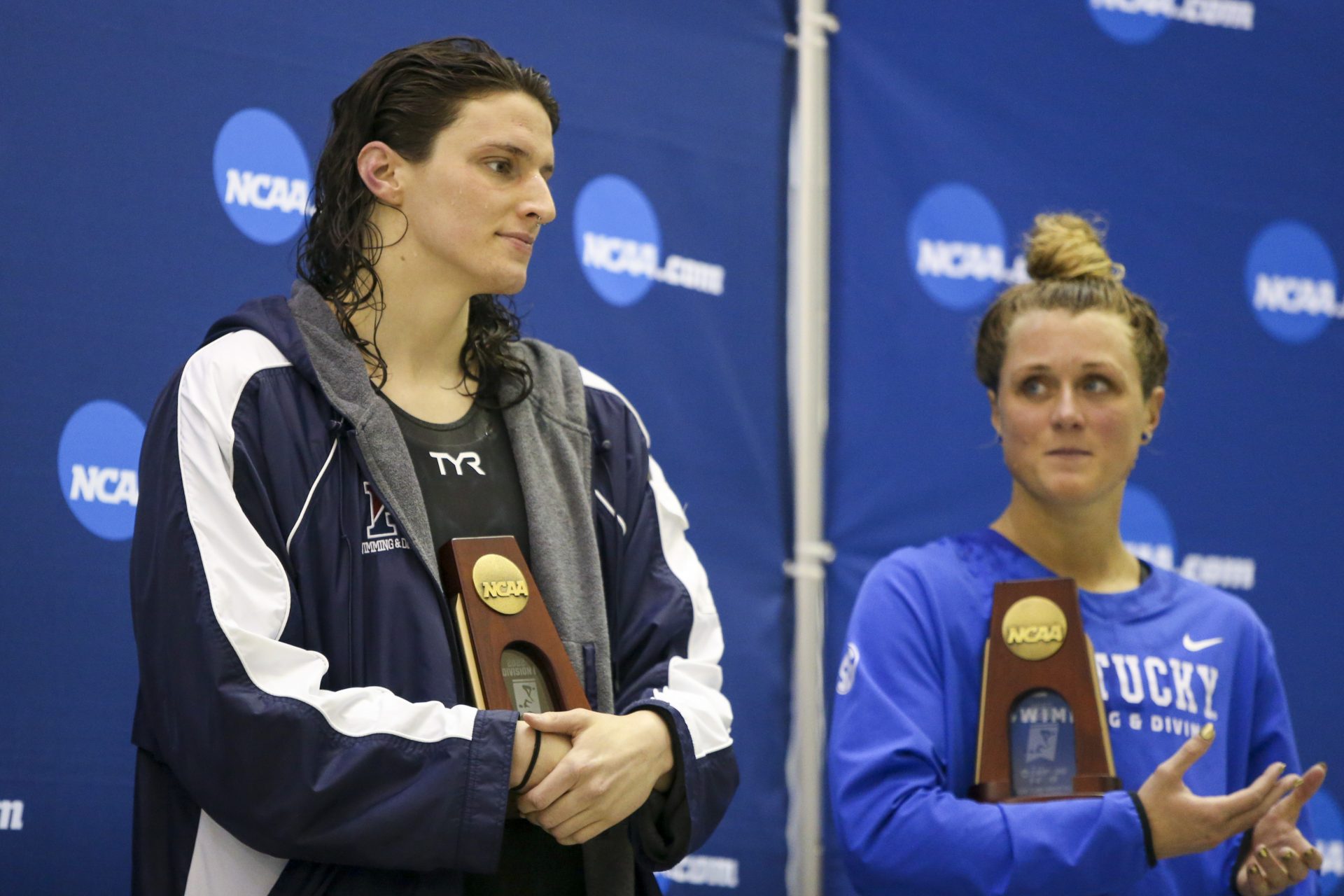 Penn Quakers swimmer Lia Thomas holds a trophy after finishing fifth in the 200 free at the NCAA Swimming & Diving Championships as Kentucky Wildcats swimmer Riley Gaines looks on at Georgia Tech.