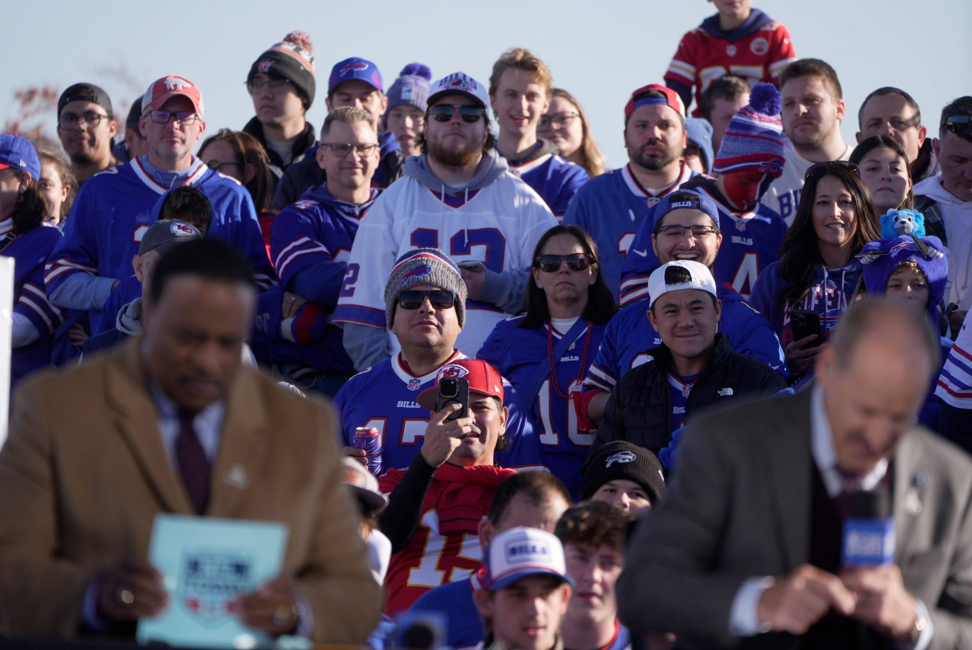 Fans watch CBS NFL announcers James Brown and Bill Cowher go over their notes before they go on the air outside the stadium hours before the Bills home game against the Kansas City Chief at Highmark Stadium in Orchard Park on Nov. 2, 2025.
