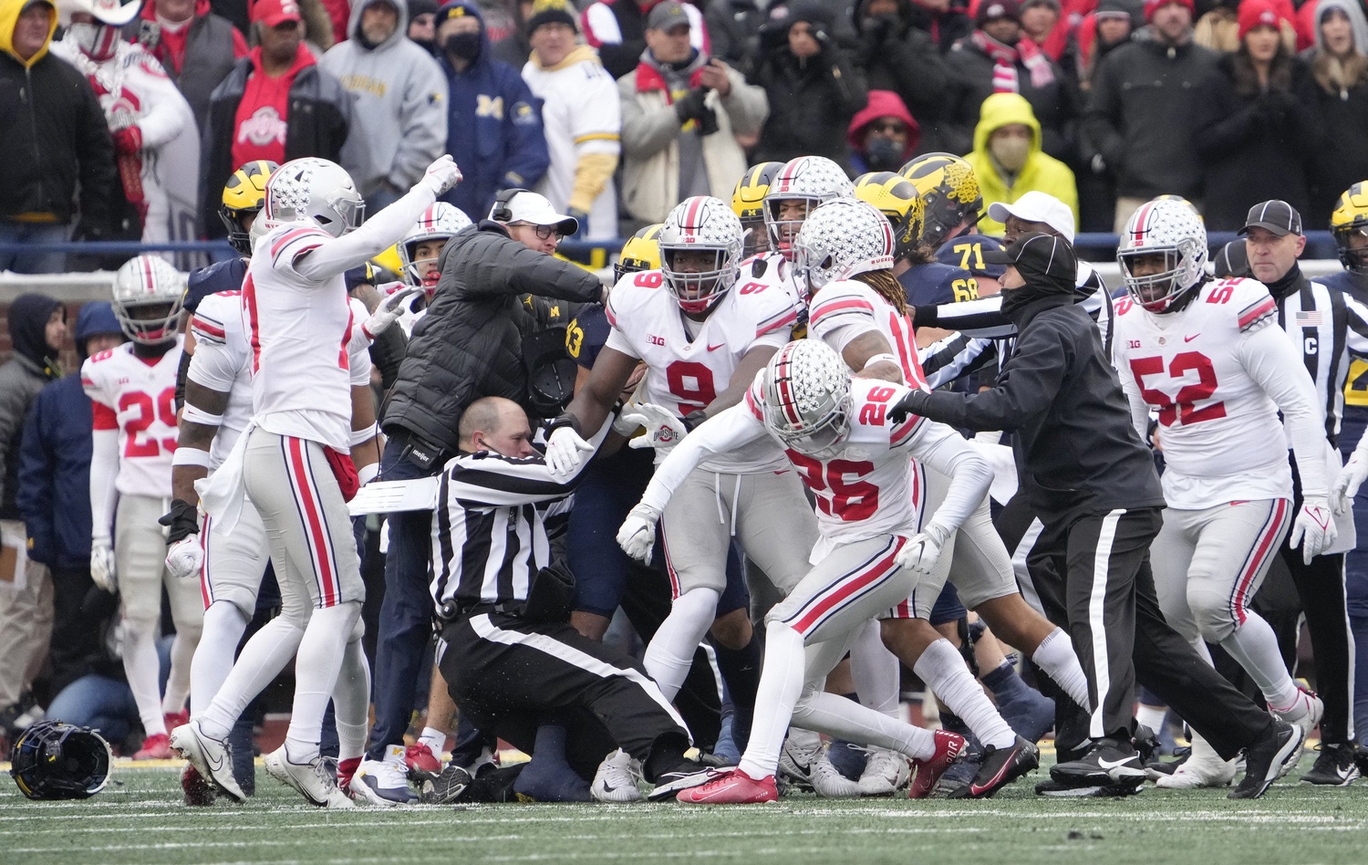A referee is knocked to the ground during a melee involving Ohio State Buckeyes cornerback Cameron Brown (26) during the third quarter of the NCAA football game against the Michigan Wolverines at Michigan Stadium in Ann Arbor on Saturday, Nov. 27, 2021.