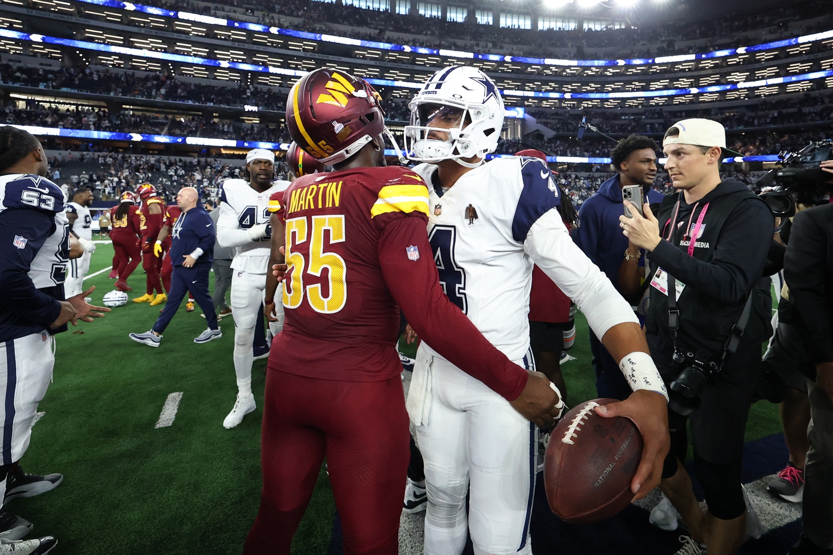 Washington Commanders defensive end Jacob Martin (55) and Dallas Cowboys quarterback Dak Prescott (4) hug after the game at AT&T Stadium.
