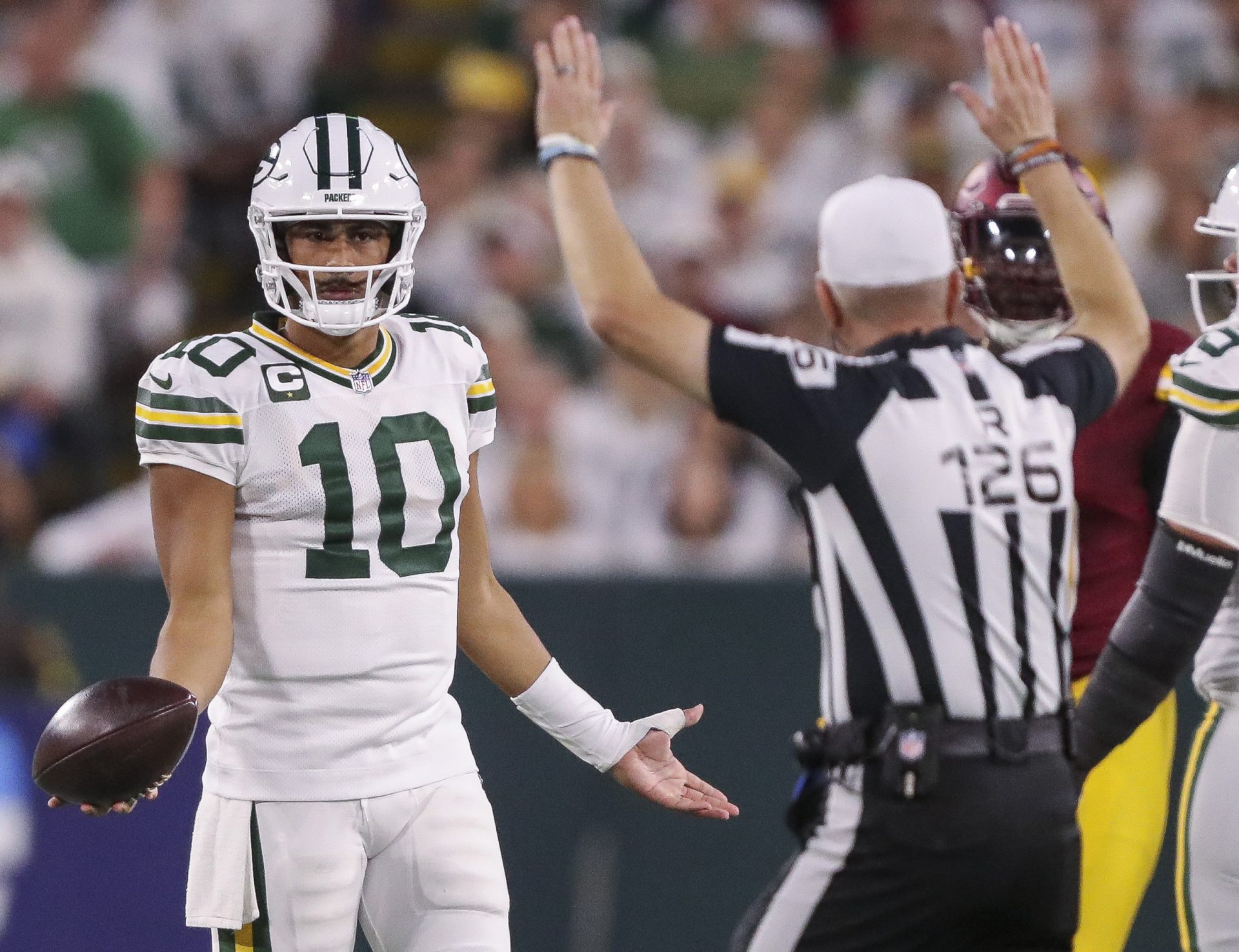 Green Bay Packers quarterback Jordan Love (10) gestures to referee Brad Rogers (126) after the Packers are called for a penalty during a game against the Washington Commanders at Lambeau Field.