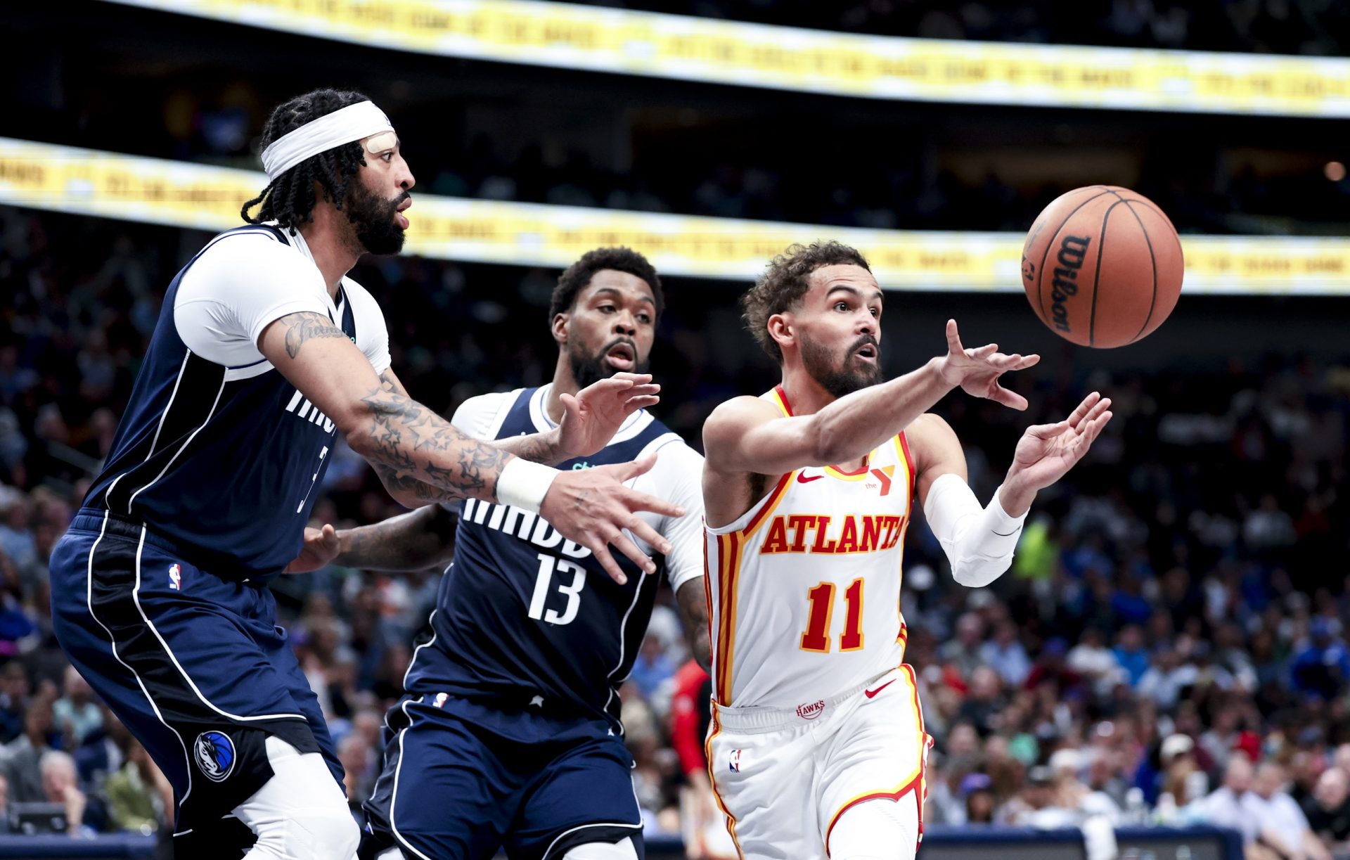 Atlanta Hawks guard Trae Young (11) passes the ball as Dallas Mavericks forward Naji Marshall (13) and Dallas Mavericks forward Anthony Davis (3) defend during the fourth quarter at American Airlines Center.