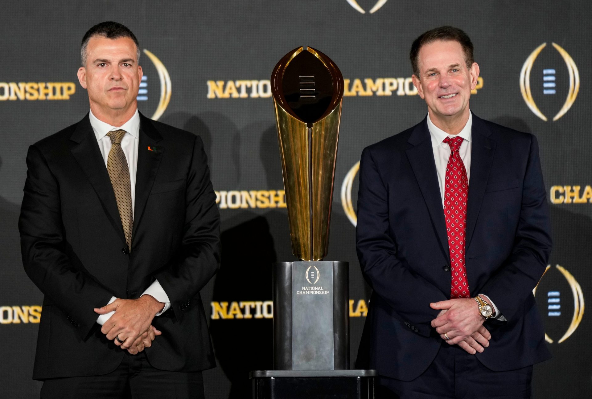 Miami Hurricanes head coach Mario Cristobal (left) and Indiana Hoosiers head coach Curt Cignetti pose for a photo Sunday, Jan. 18, 2026, during a press conference ahead of the College Football Playoff Championship in Miami.