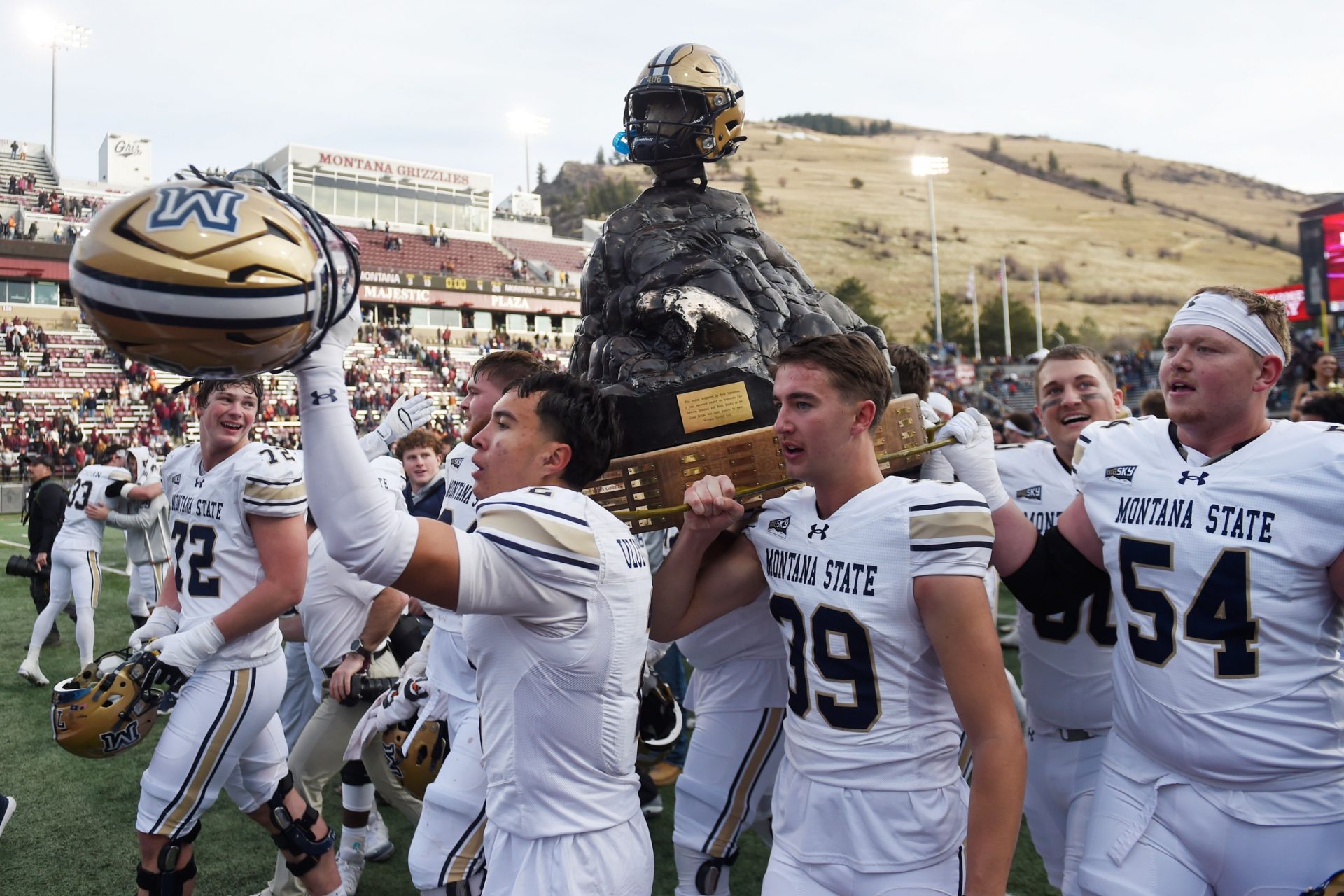 Montana State Bobcats safety Taki Uluilakepa (2), kicker Myles Sansted (39), and offensive lineman Zac Nyland (54) celebrate with the Great Divide Trophy after defeating the Montana Grizzlies at Washington-Grizzly Stadium.