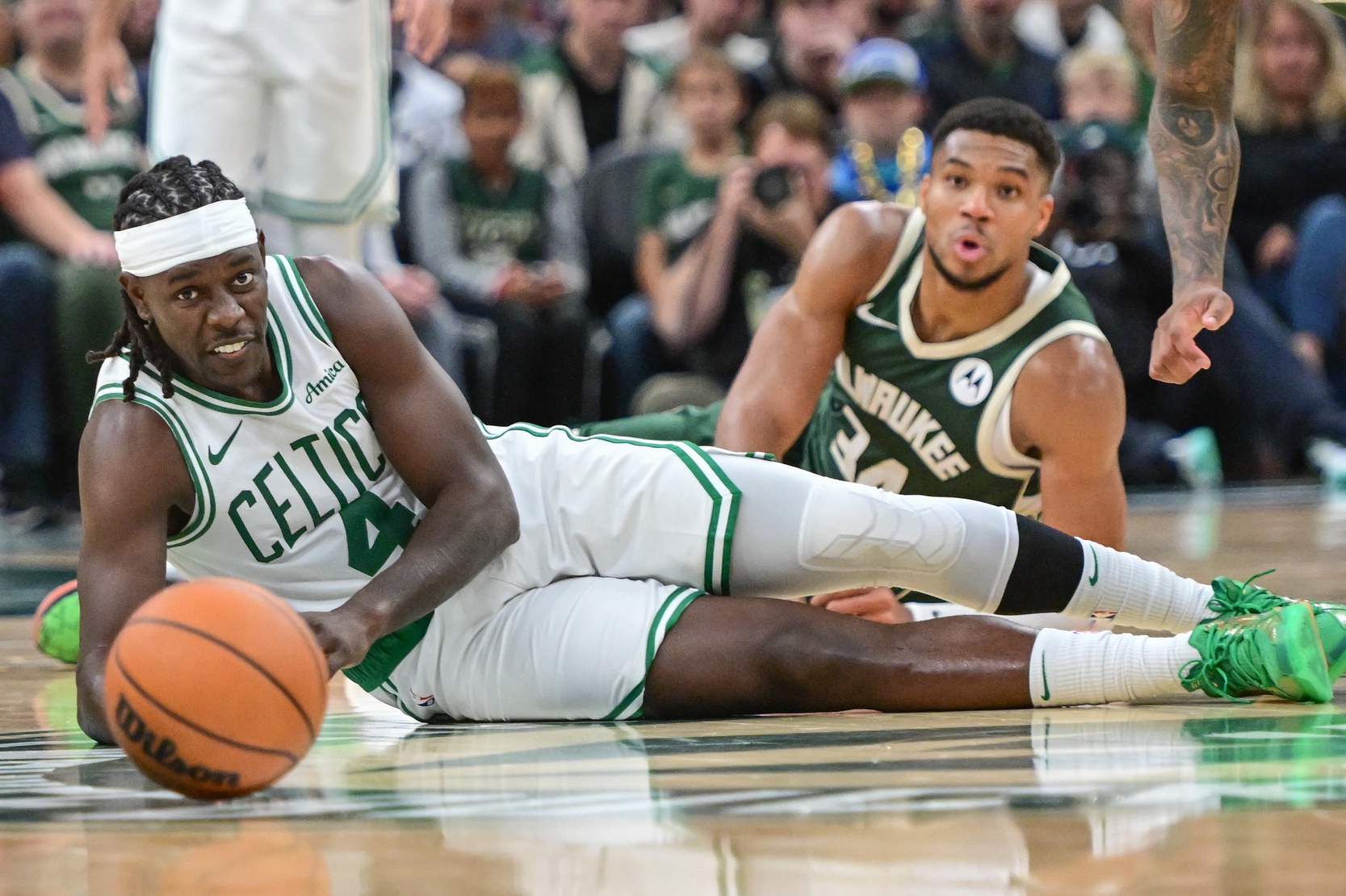 Milwaukee Bucks forward Giannis Antetokounmpo (34) and Boston Celtics guard Jrue Holiday (4) reach for a loose ball in the fourth quarter at Fiserv Forum.