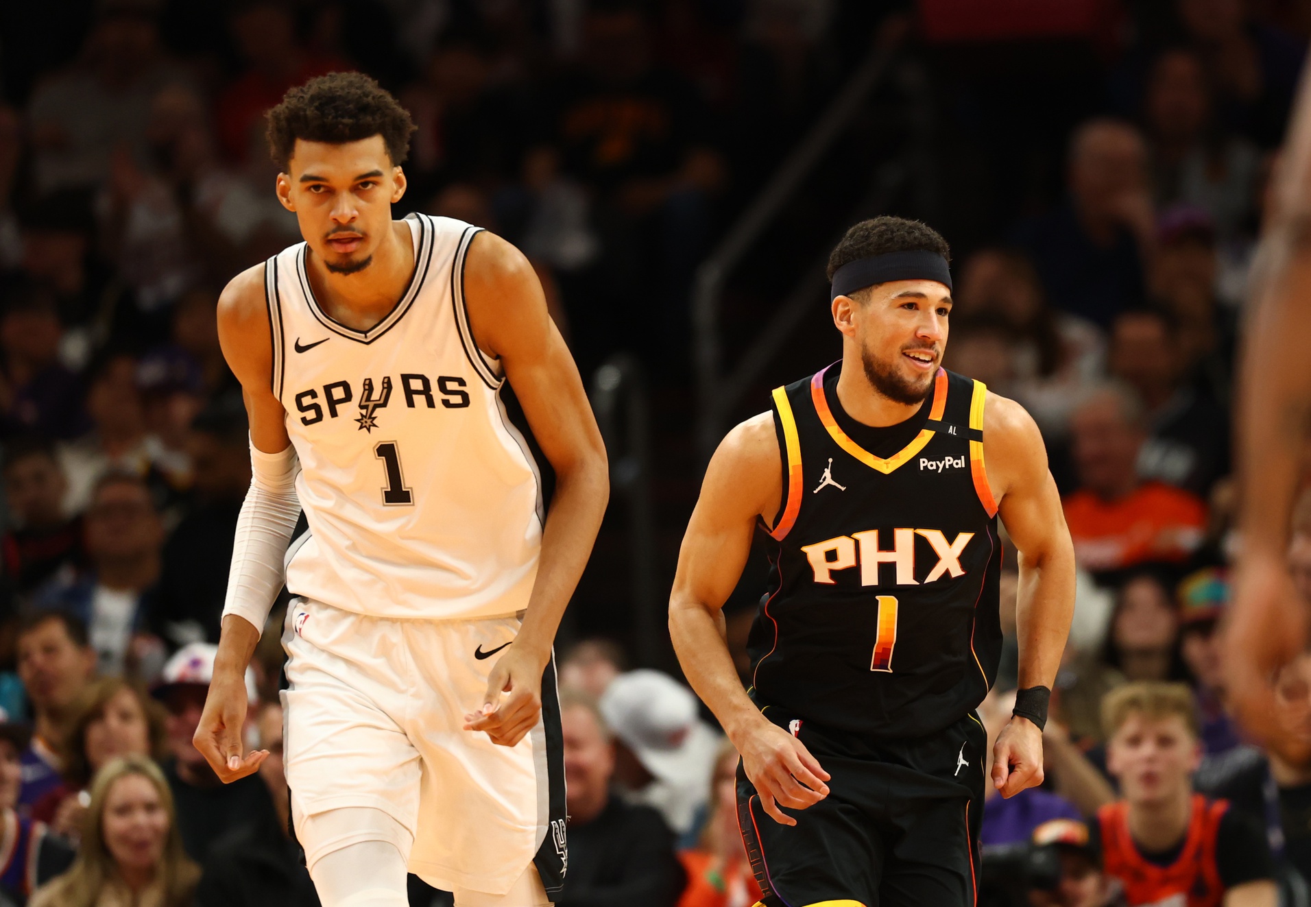 Phoenix Suns guard Devin Booker (right) against San Antonio Spurs center Victor Wembanyama in the first half of an NBA Cup game at Footprint Center.
