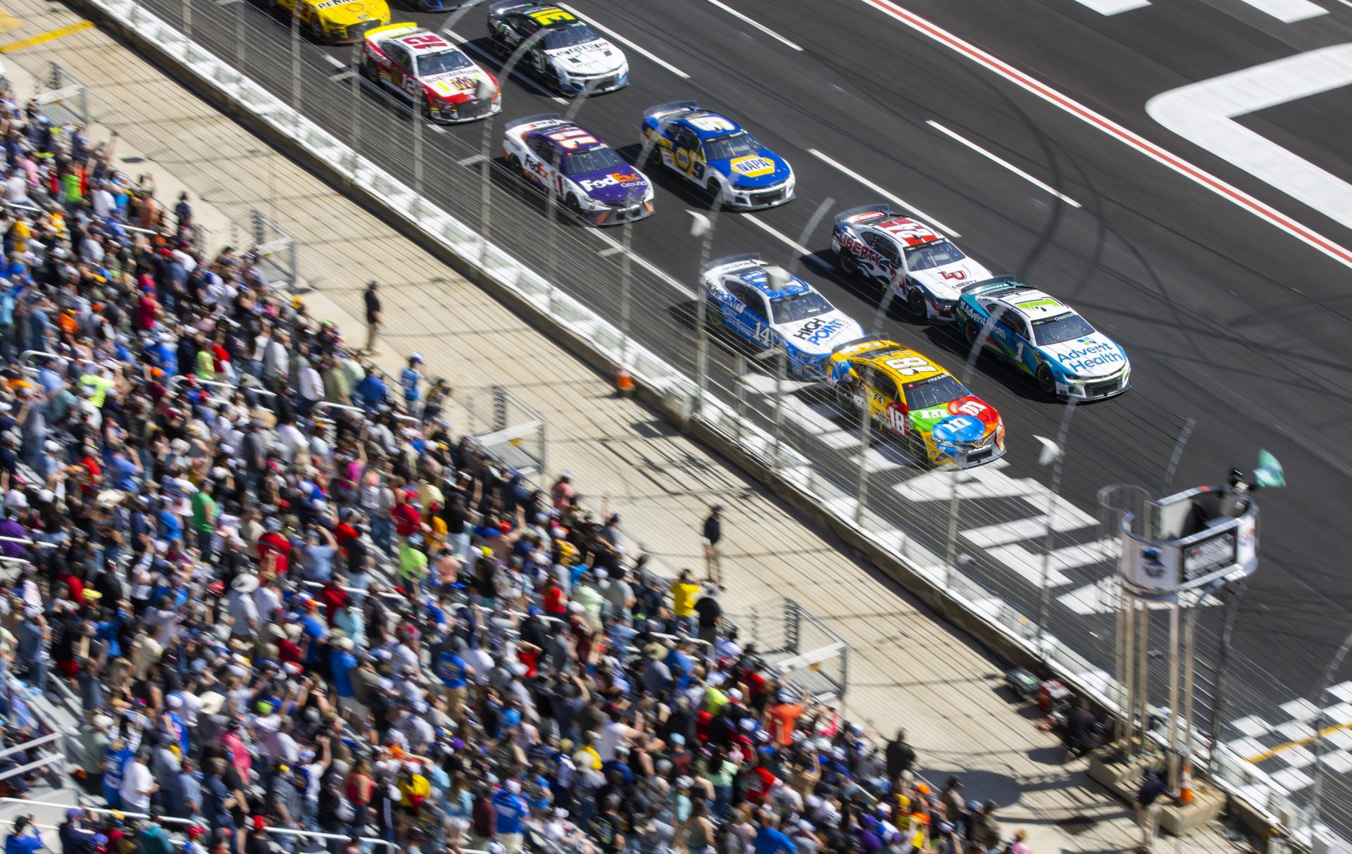 Fans look on as the field of NASCAR Cup Series drivers led by Ross Chastain (1) and Kyle Busch (18) take the green flag on a restart during the Folds of Honor QuikTrip 500 at Atlanta Motor Speedway.