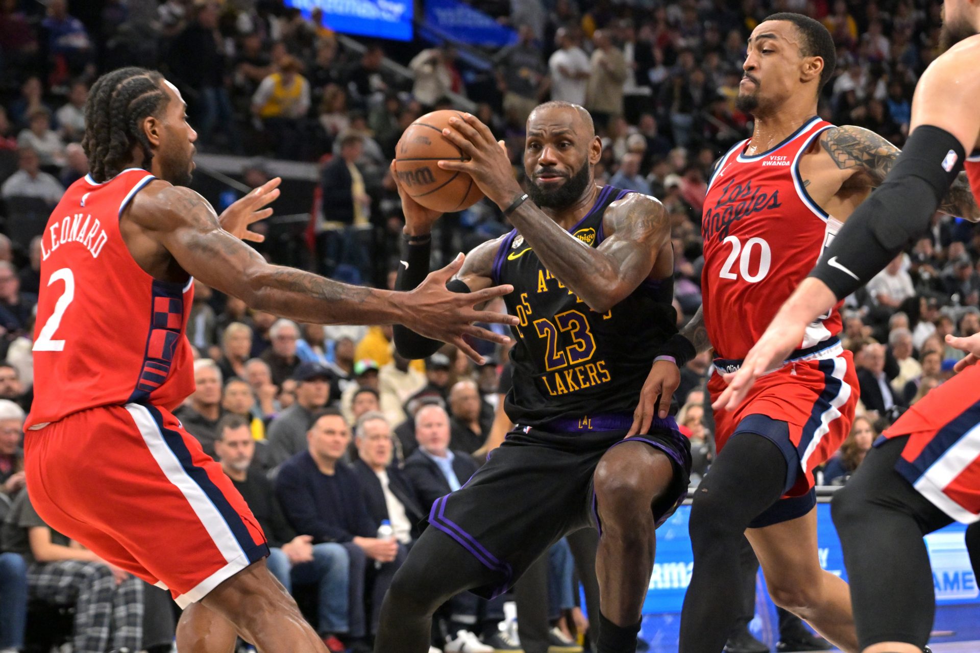 Los Angeles Clippers forward Kawhi Leonard (2) and forward John Collins (20) defend Los Angeles Lakers forward LeBron James (23) as he drives to the basket in the second half at Intuit Dome.