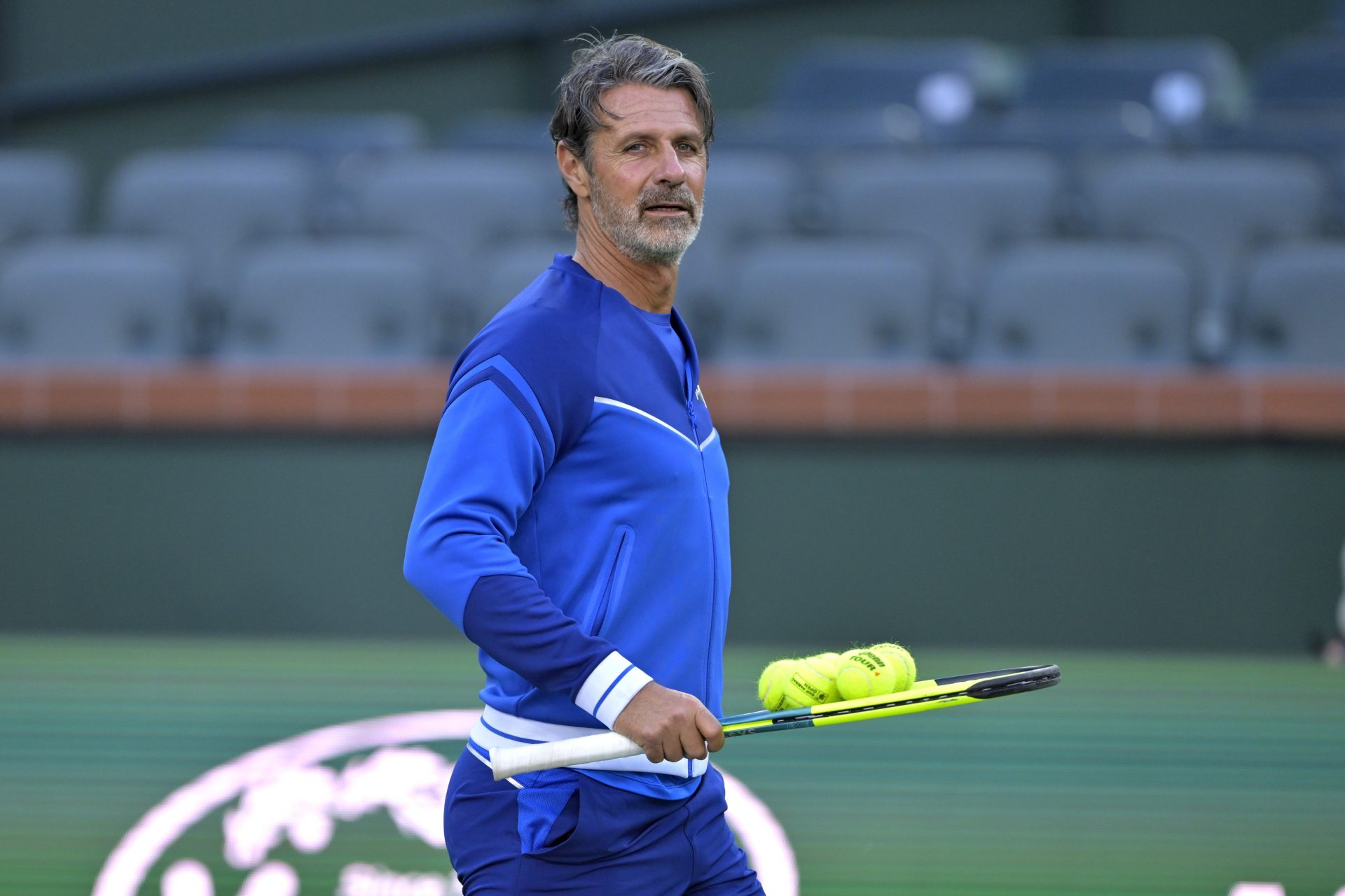 Patrick Mouratoglou, coach of Naomi Osaka, picks up some practice balls during the first day of the BNP Paribas open at the Indian Well Tennis Garden.