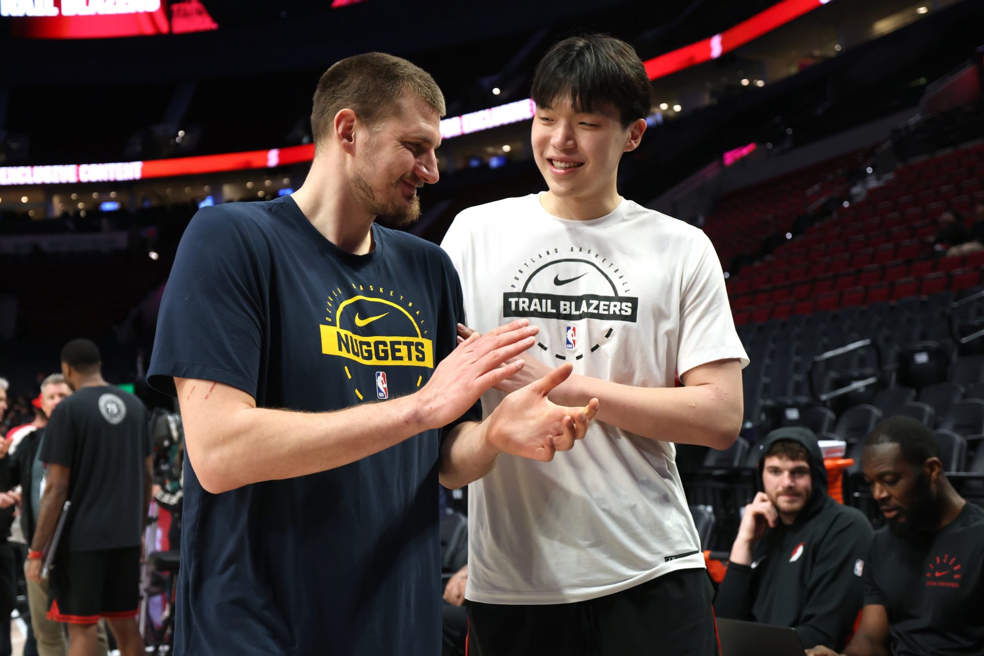 Denver Nuggets center Nikola Jokic (15) and Portland Trail Blazers center Yang Hansen (16) talk during warm ups at Moda Center.