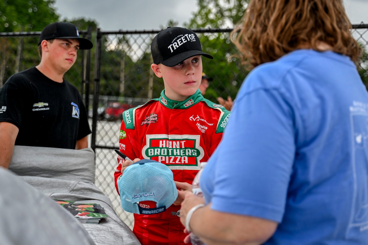 13-year-old Keelan Harvick, son of former NASCAR Cup Series champion Kevin, signs items for fans during an autograph session before the 13th annual Masters of the Pros 200 race on Wednesday, July 16, 2025, at the Owosso Speedway. Keelan and his father competed against each other in the race later in the night.